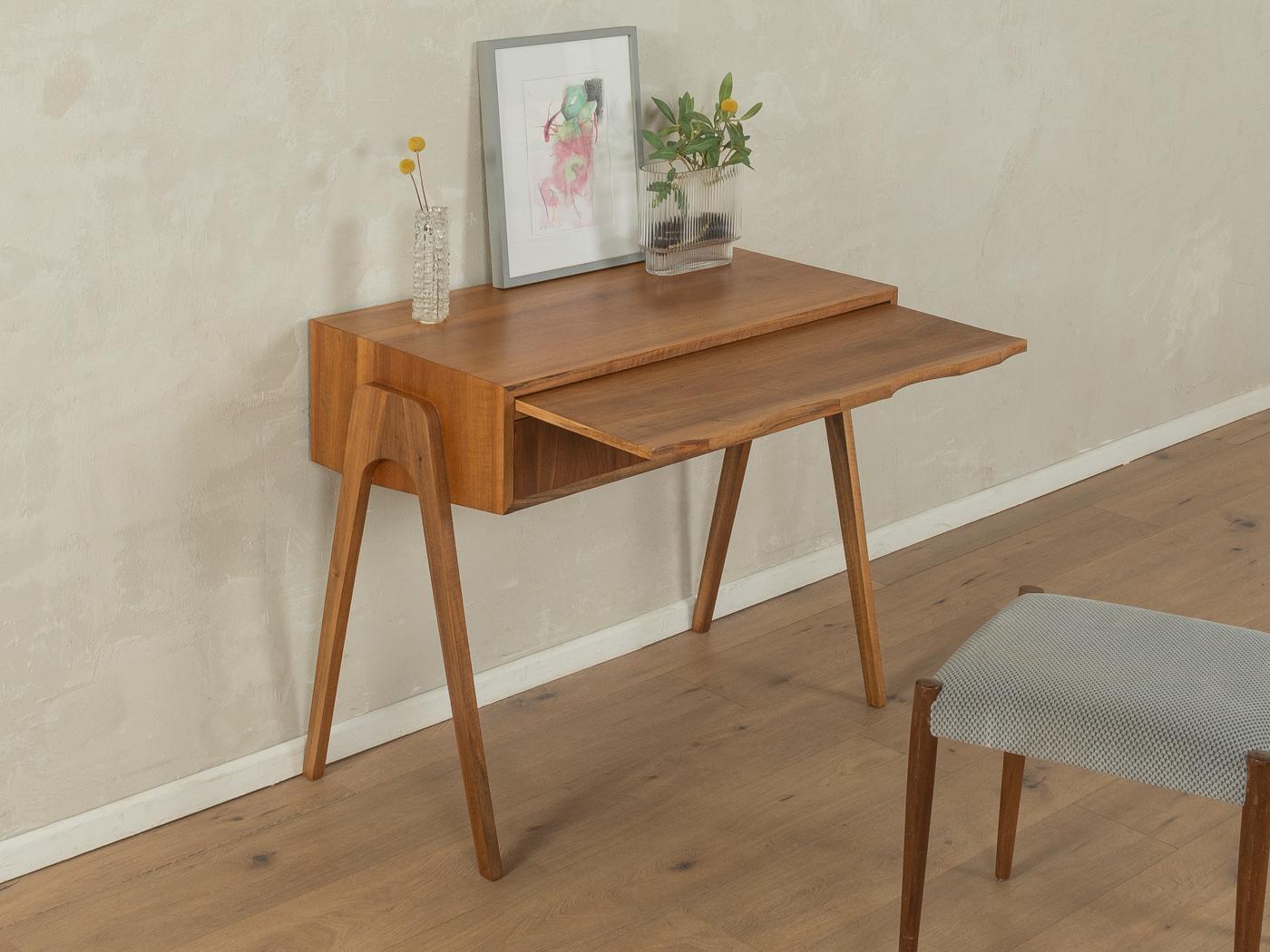 Unique dressing table from the 1950s. High-quality corpus in walnut veneer with one drawer, one pull-out writing surface and slanted solid wood legs.

Quality Features:
very good workmanship
high-quality materials
mortise & tenon solid wood