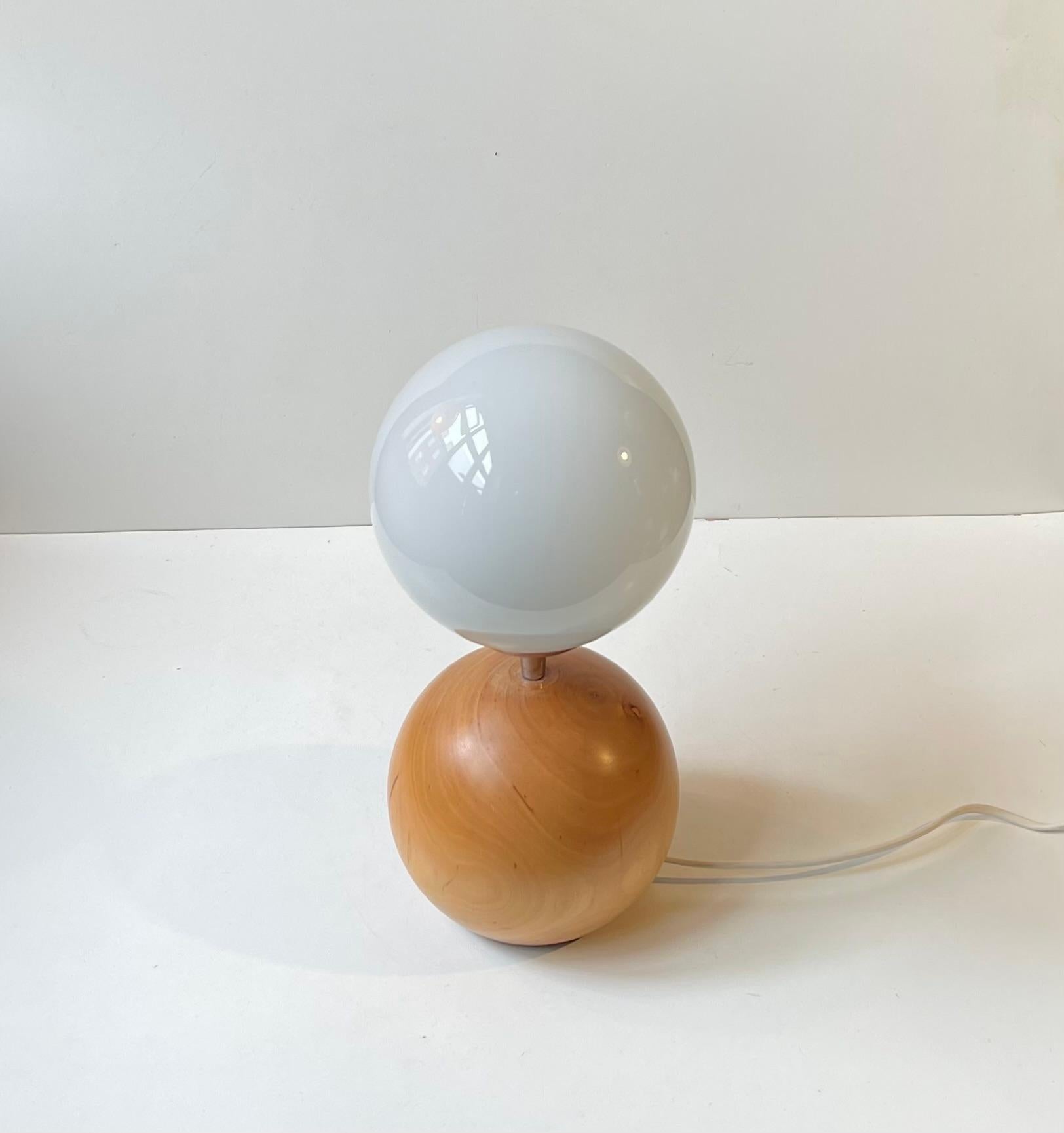 Lámpara de sobremesa moderna, inusual y escultural, realizada con una gran esfera maciza de madera de haya y con una esfera/pantalla de cristal opalino de tamaño similar. Una esfera sobre otra esfera. Fabricante/diseñador escandinavo desconocido de