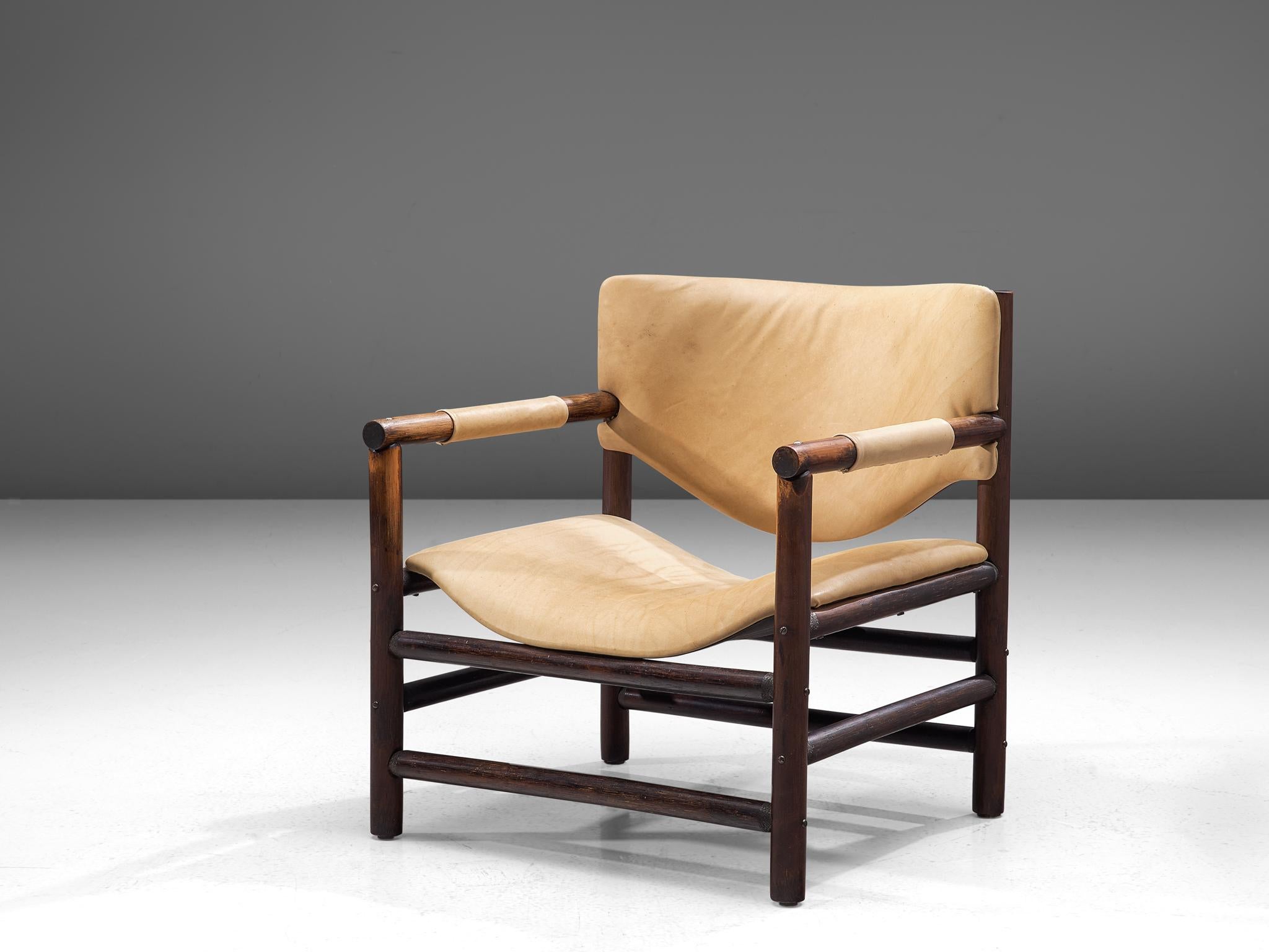 Fauteuil, cuir et chêne, Scandinavie, années 1960

Un magnifique fauteuil rustique avec un cadre géométrique en bois composé de lignes horizontales et verticales fortes. L'assise et le dossier, revêtus de cuir naturel, sont de forme organique, ce
