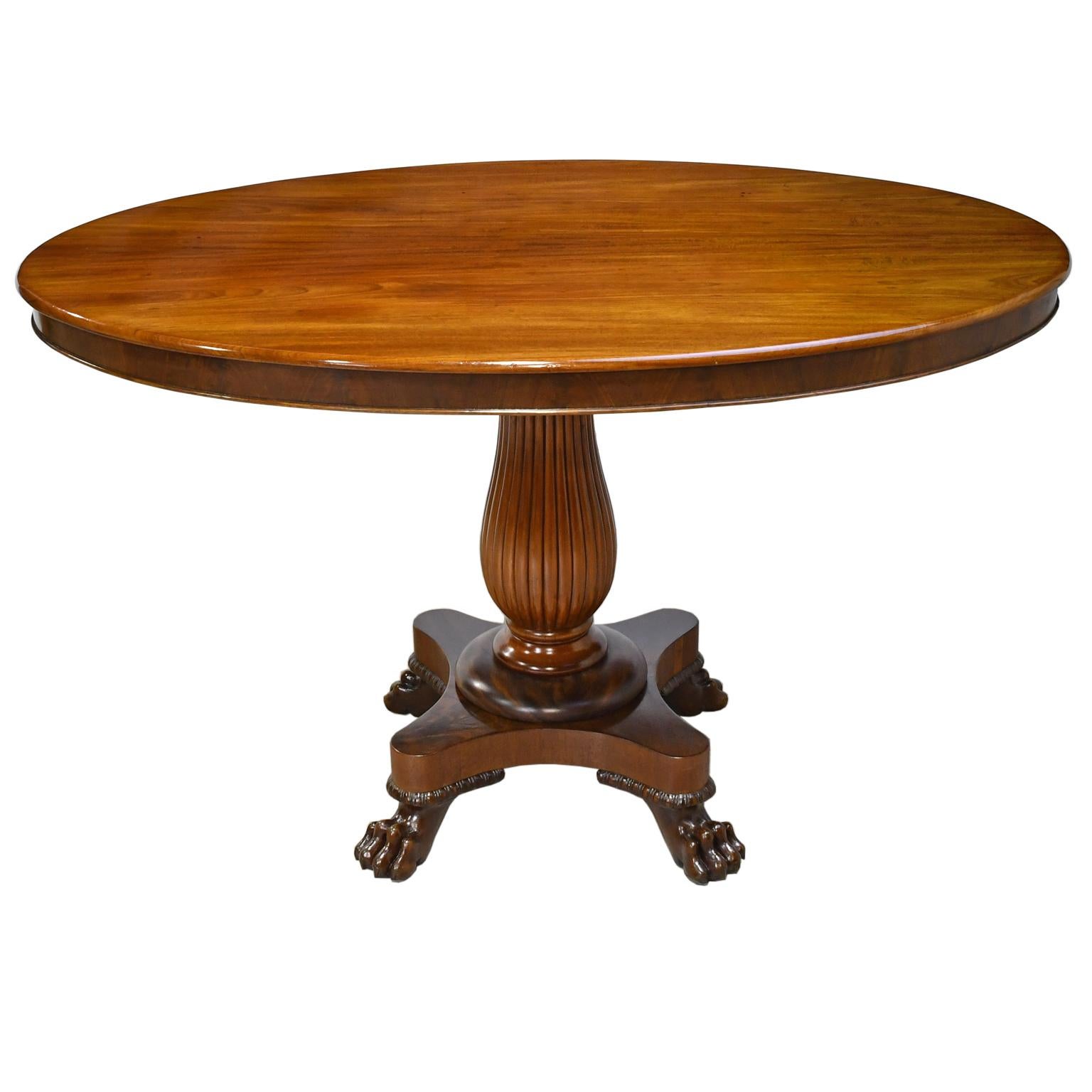 An exceptional Empire salon or tea table in fine West Indies mahogany with oval top on vase-turned and fluted column resting on quatre-form pedestal base with carved lions' paw feet. Denmark, circa 1825. Historically, this table would have graced a
