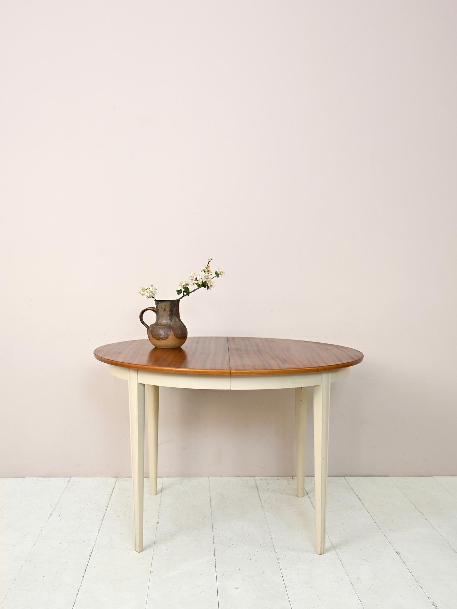 Round wooden table with white painted legs.

A piece of furniture with a shabby chic flavor, Scandinavian original from the 1960s.
Thanks to the central axis it can be extended and comfortably seat 6 people.
An original table ideal for a home with a