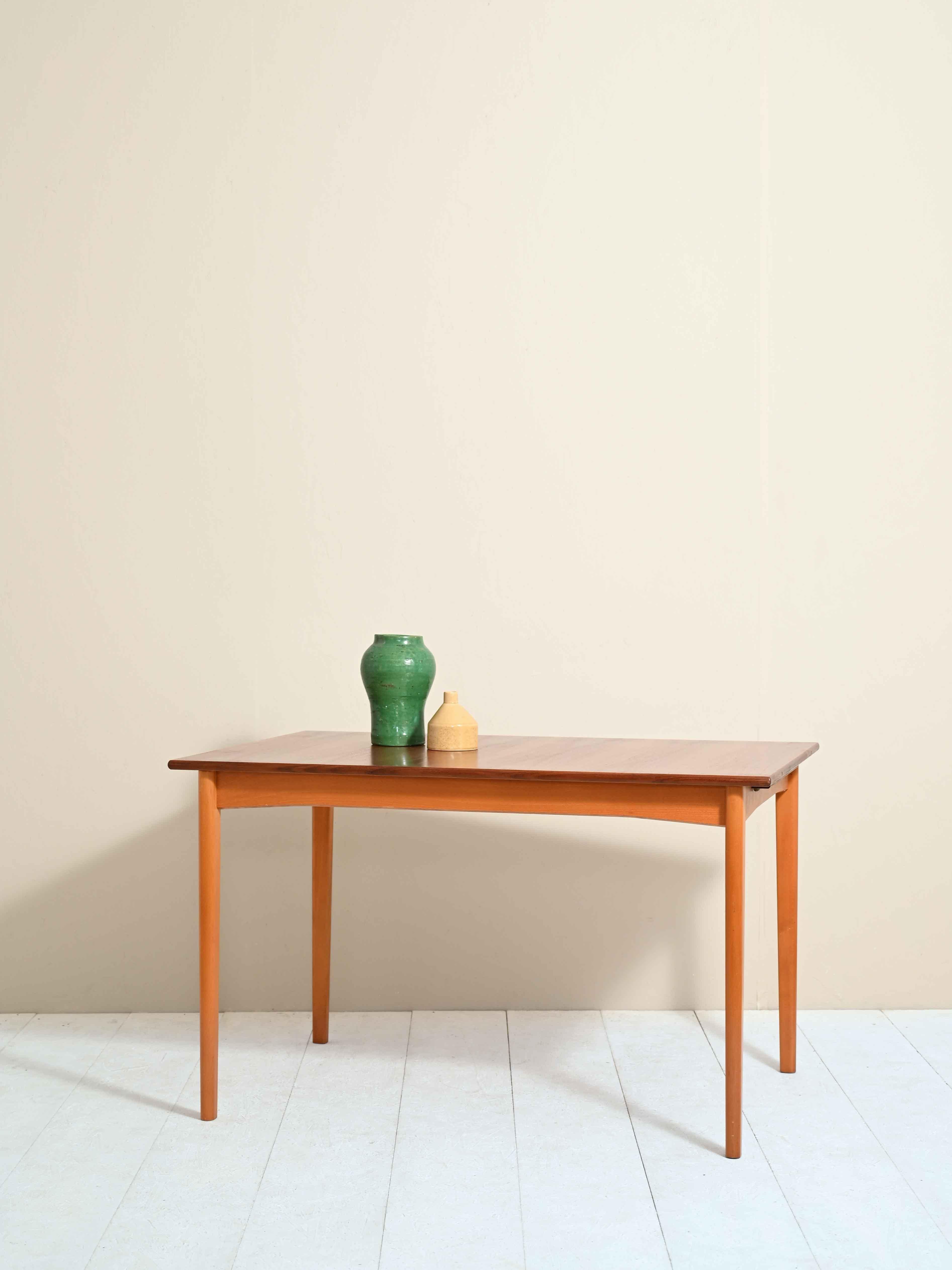 Rectangular dining table, original 1960s.
 
Characterized by simple, minimalist shapes, it can be extended by 47 cm thanks to a removable wing to be used as a tabletop or as an additional seat.
 
Long conical legs, typical of Nordic design, are