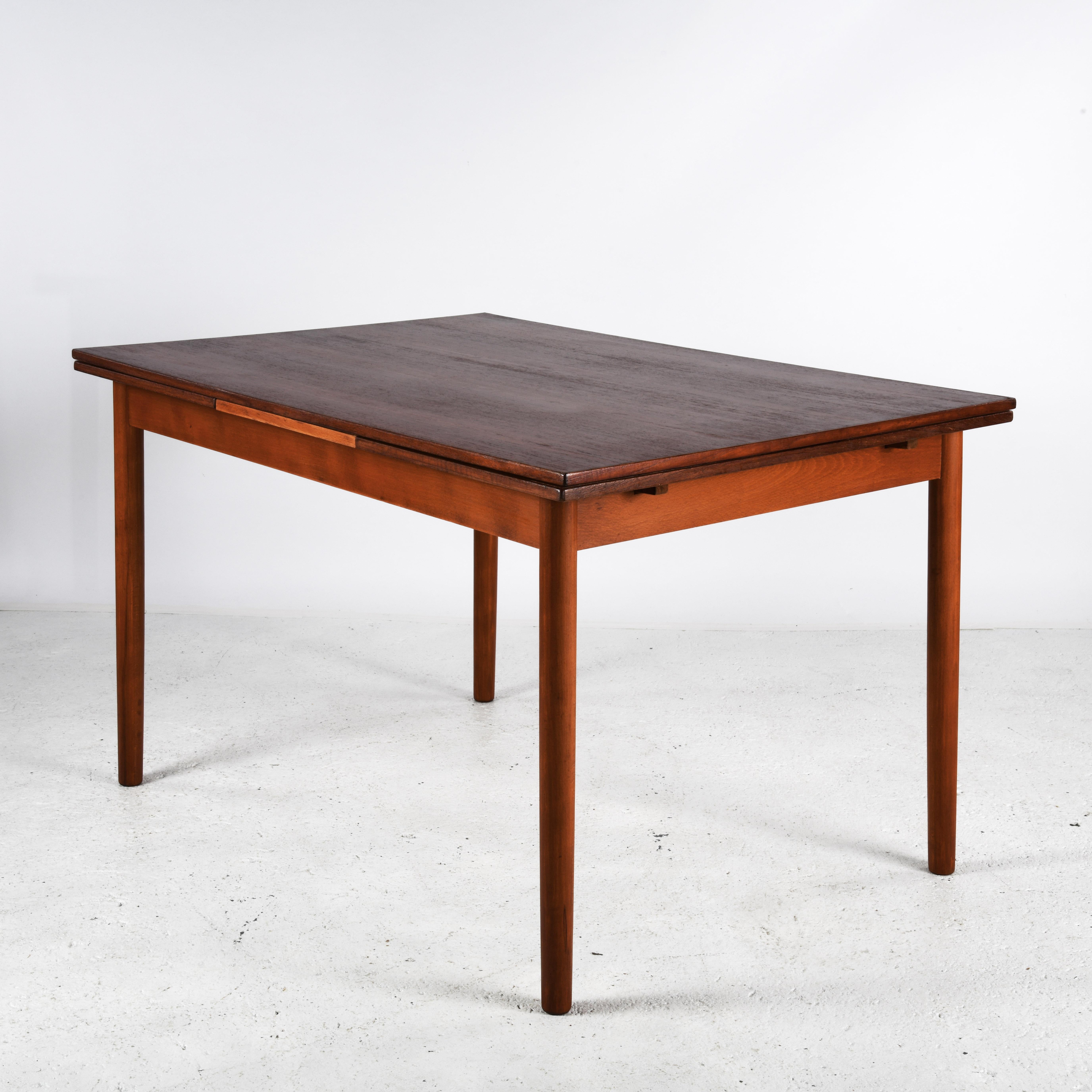 Esstisch aus Teakholz aus Dänemark, hergestellt in den 1960er/70er Jahren. Der Tisch hat eine Platte und zwei ausziehbare Blätter darunter. Die Platten sind mit einem Satinlack geschützt und können ohne Tischtuch verwendet werden. Die Beine lassen