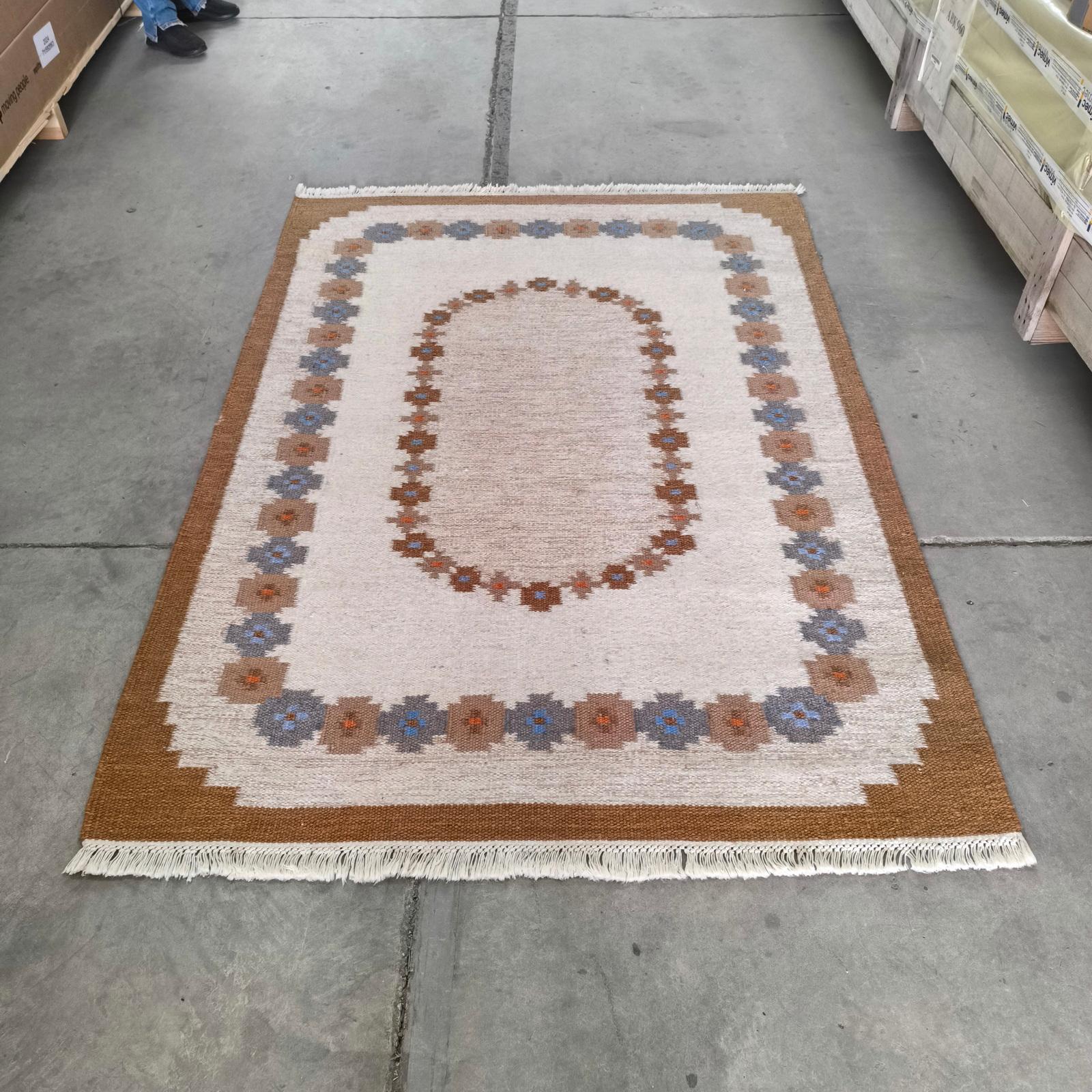 Tapis suédois vintage à tissage plat Röllakan à motifs géométriques dans les tons de brun, Suède, années 1970.
Röllakan authentique en laine, tissé à la main. Guirlandes florales stylisées dans un champ beige doux, délimité par une bordure