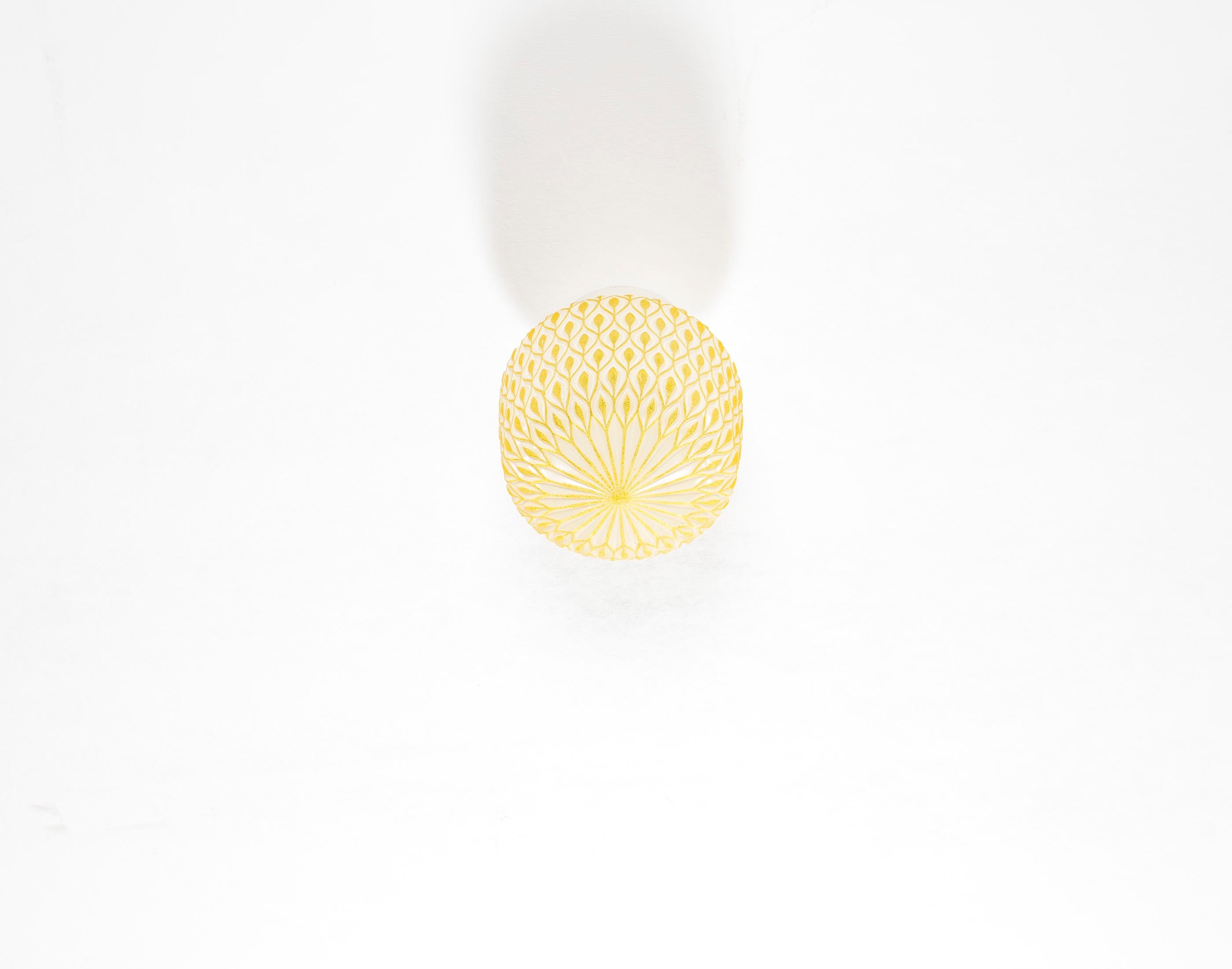 Decorative ceiling light in yellow glass with embossed surface and base in porcelain. Designed and made in Norway from circa 1950s first half. The lamp is fully working and in very good vintage condition. The lamp uses a E27 bulb (works in the US),