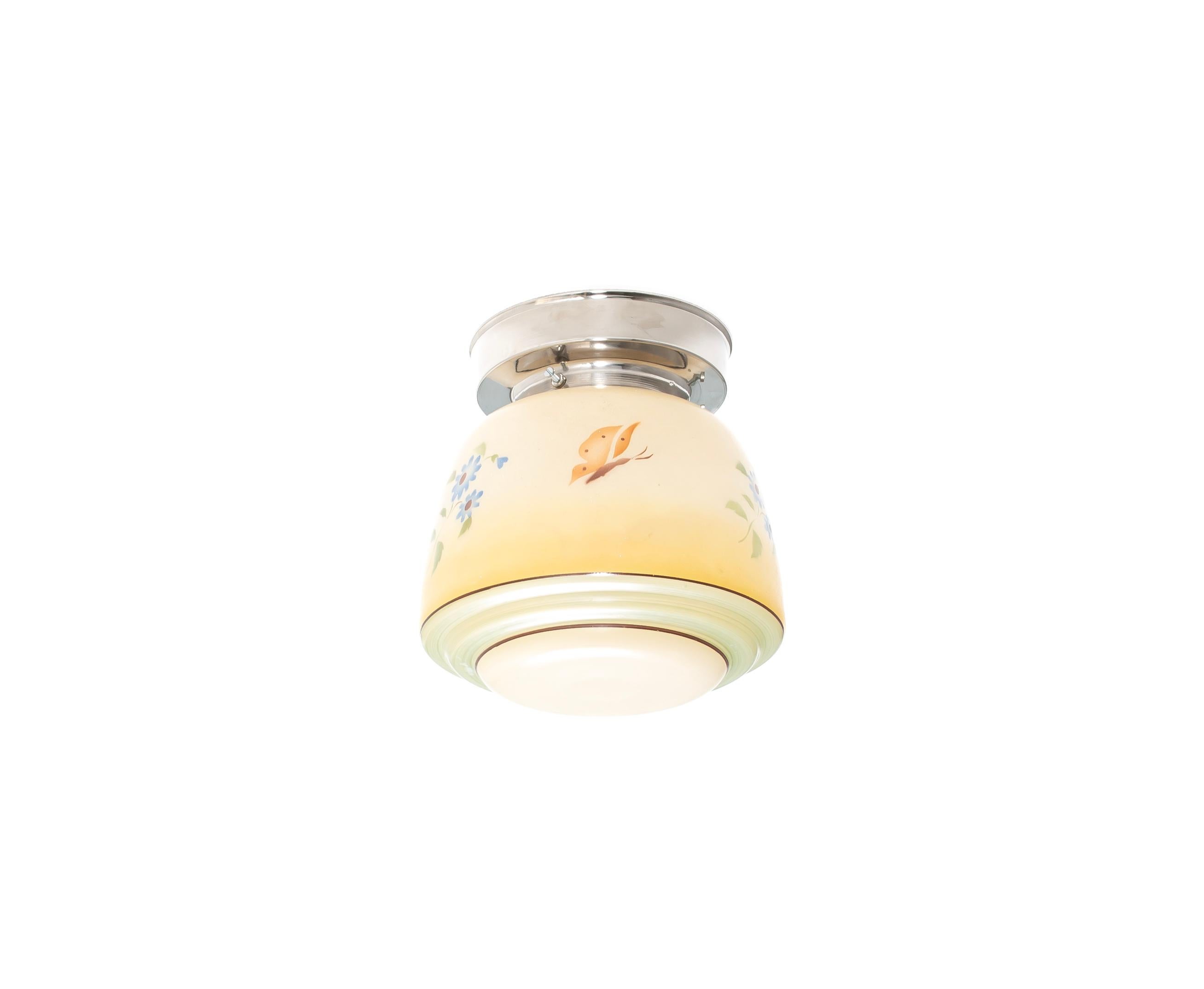 Decorative ceiling light featuring a glass shade in hand-painted floral patterns and a chrome metal base. Designed and made in Sweden from ca 1950s first half. The glass shade is finished in a warm cream tone and decorated with hand-painted floral