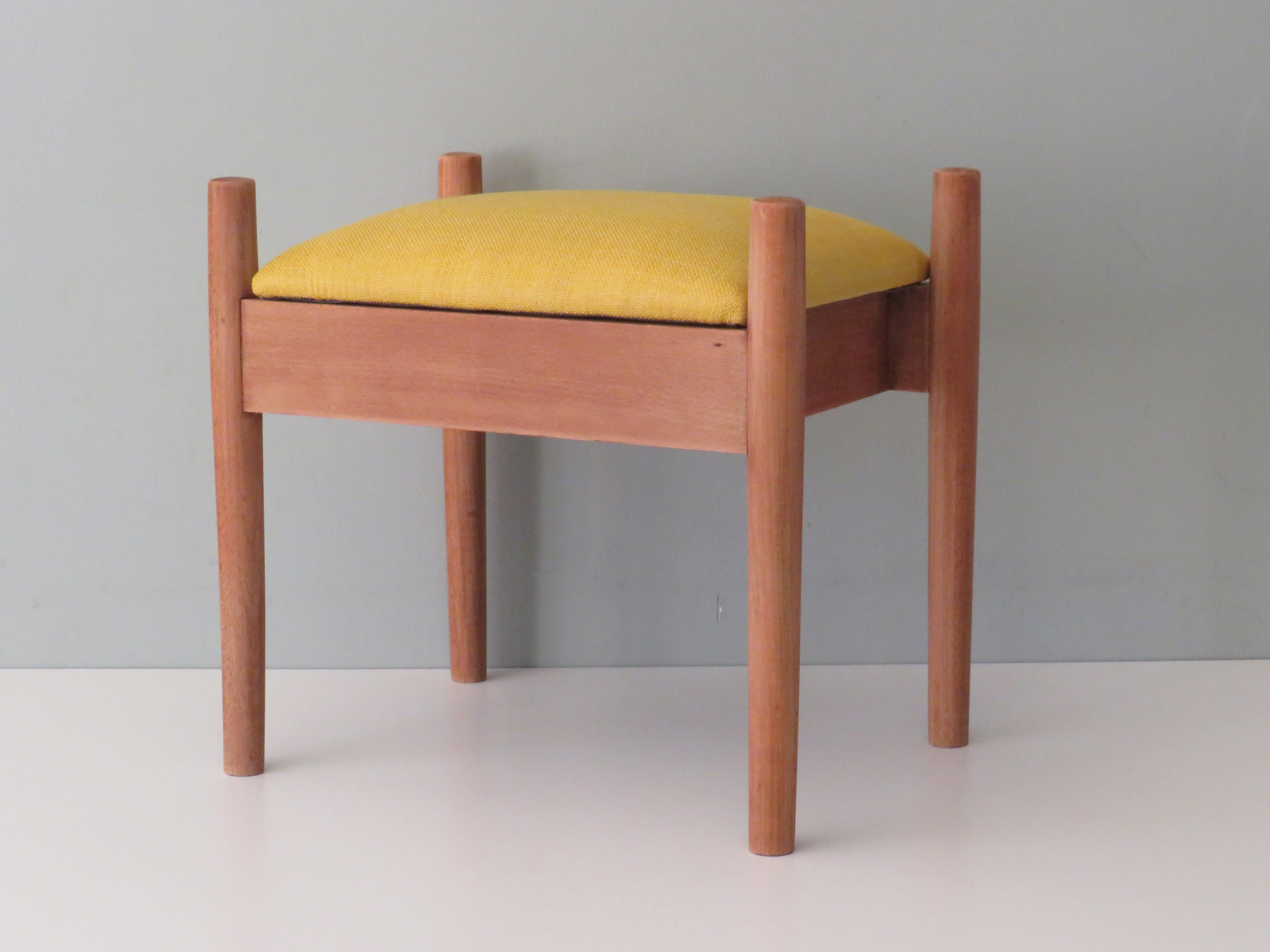 The wooden footstool has a new upholstery of a high-quality yellow woven fabric.