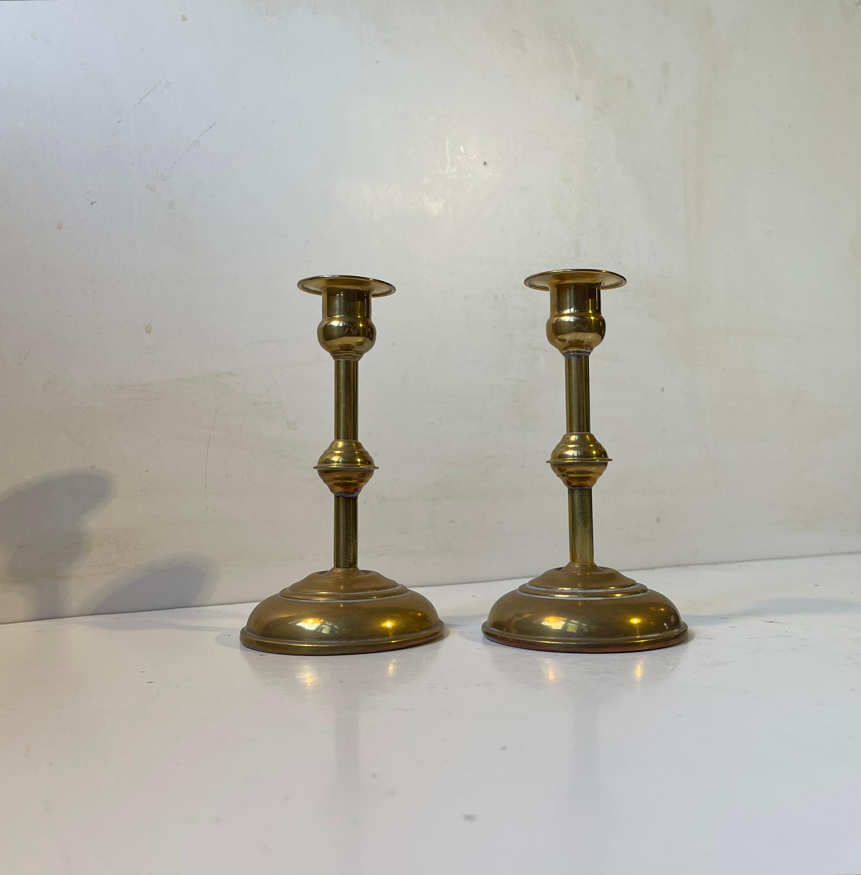 A pair of brass candlesticks for regular sized candles. Distinct functionalist styling with architectural features. Manufactured anonymously in Scandinavia during the 1930s or 40s.   

Measurements: H: 15 cm, D: 8 cm (base).