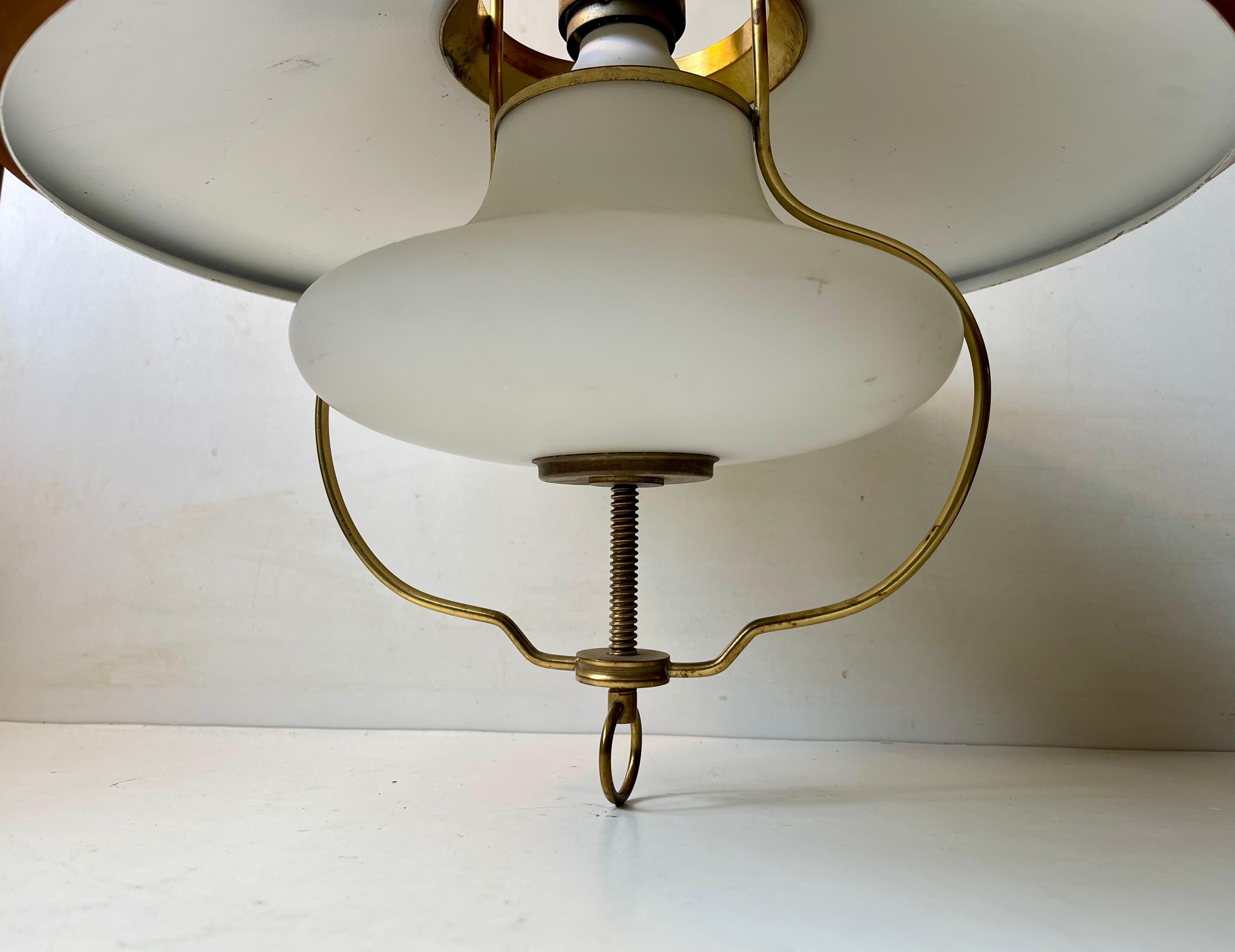 A rare internally adjustable nautical hanging lamp in solid brass, white opaline glass and copper alloy outer shade. You can adjust the spreading and intensity of the light via the stylish tomb-screw at the bottom. It was made by Lyfa in Denmark