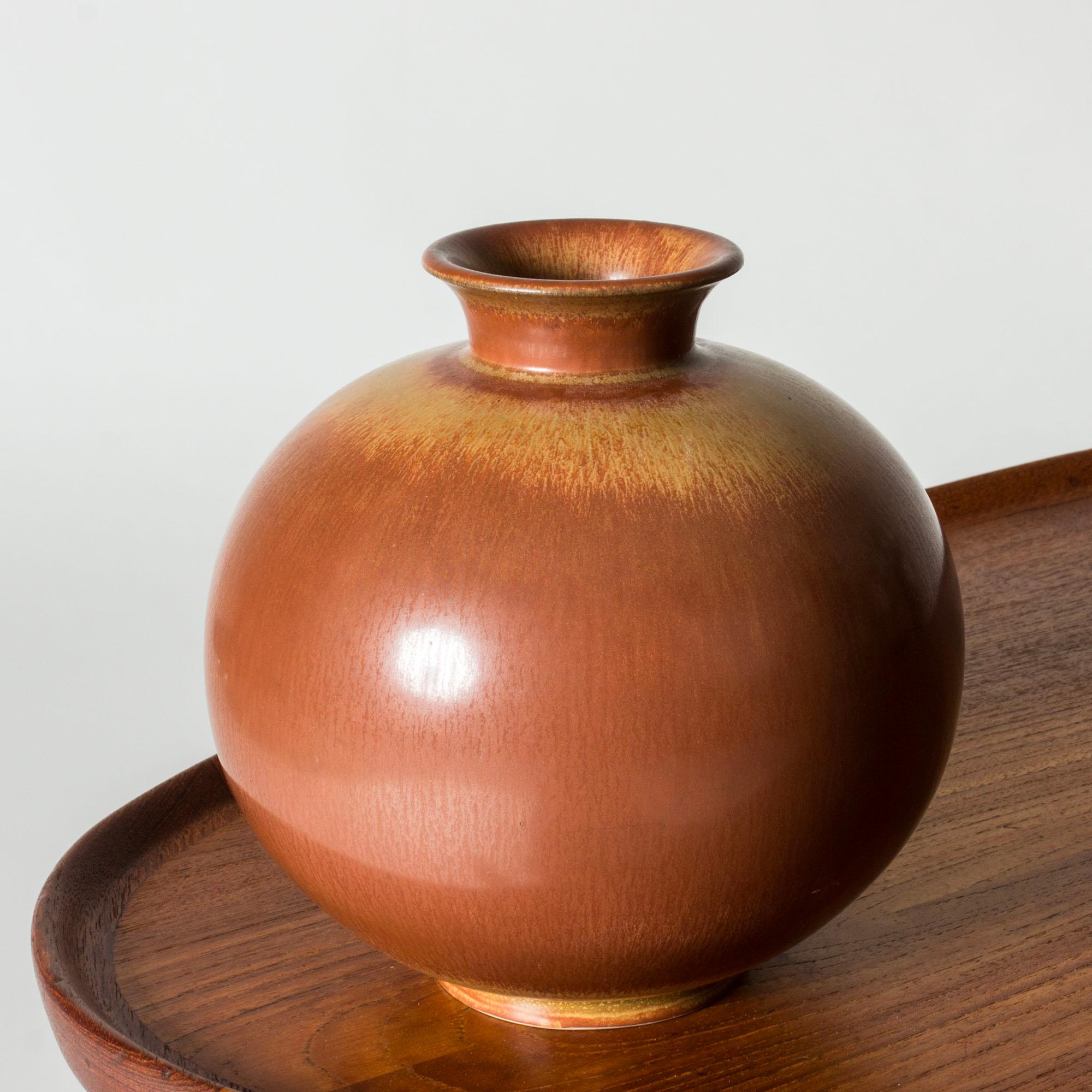 Lovely stoneware vase by Gunnar Nylund, in a rounded form. Glazed war ochre brown with a lighter brown line around the top and inside the opening.

Gunnar Nylund was one of the most influential ceramicists and designers of the Swedish mid-century