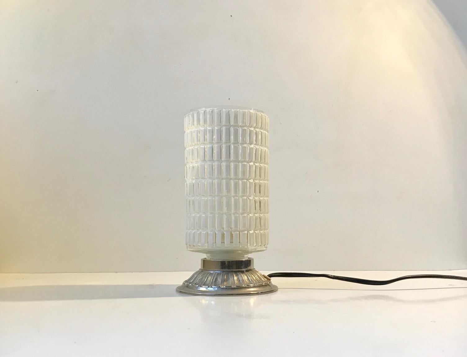 Small and unusual table light with a checkered glass shade and an aluminium base. These type of lights originally went under names as restaurant lamps or 'Dating lamps' and was intended to replace the candlesticks under dim lighting. It was made in