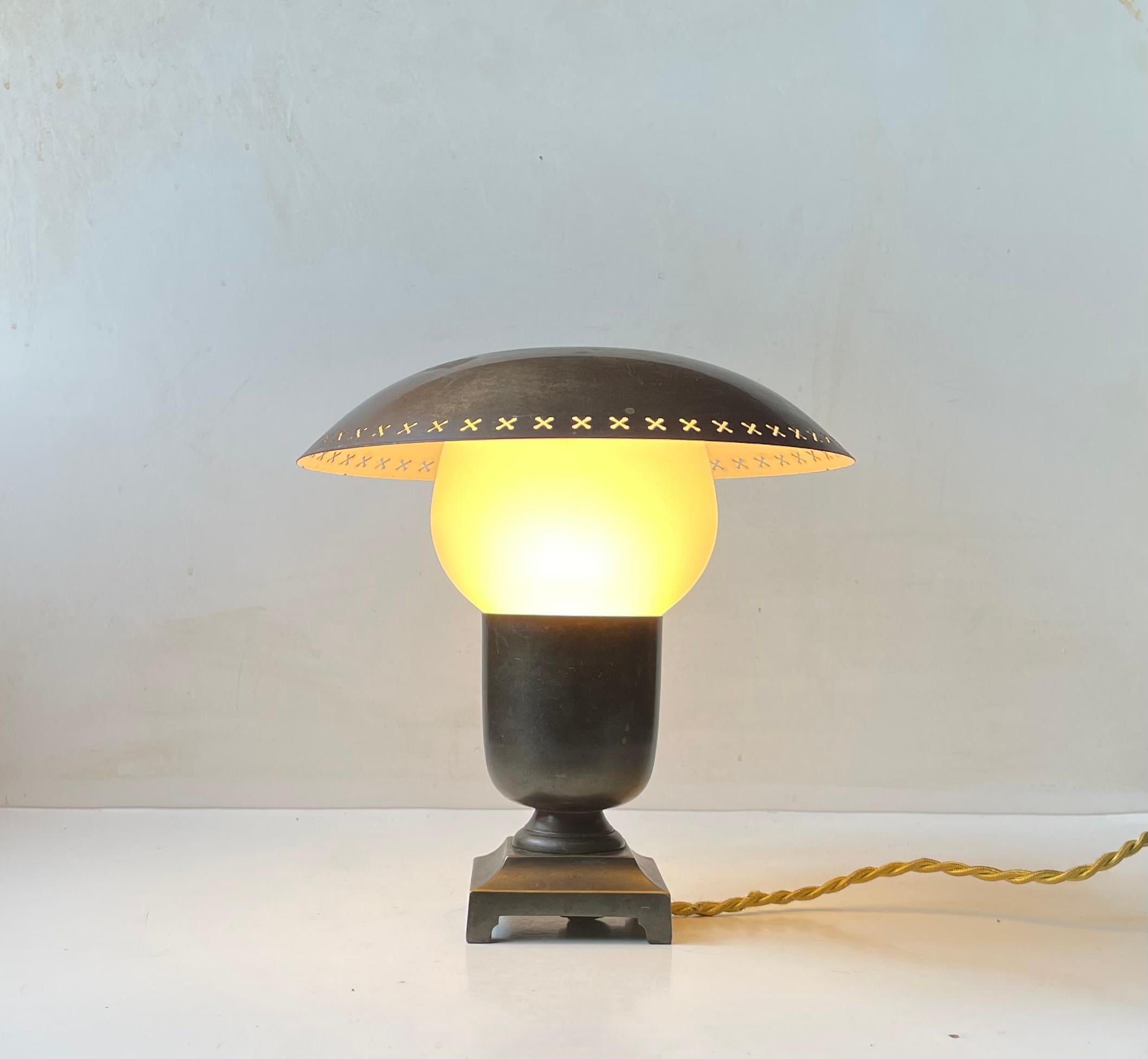 A well made possibly up-cycled table lamp made from a green verdigris bronze urne installed with a patinated brass shade rating on a frosted/matté opaline glass shade. This small table light features its original 1940s socket in bakelite. A more
