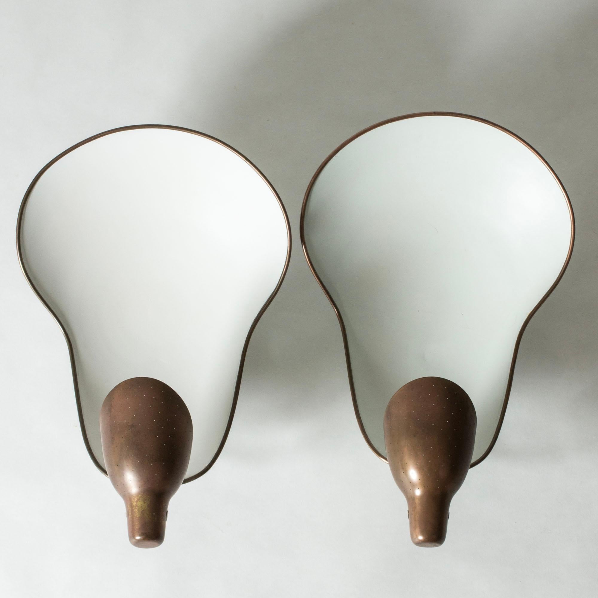 Pair of amazing wall lights by Carl-Axel Acking, in an oversized design made in brass. Large, white lacquered light plates reflect the upward light from the polka dot perforated shades.

Carl-Axel Acking was a Swedish architect, furniture designer