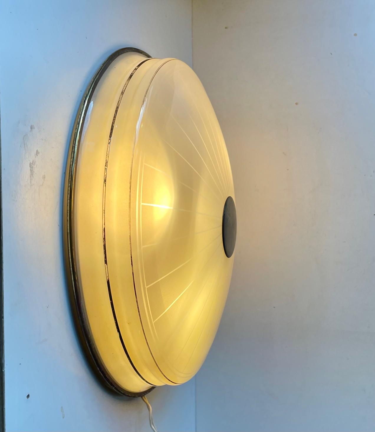 A large flush mount chandelier or wall sconce manufactured by Lyfa in Denmark during the 1950s or early 60s. The piece features a large pin-striped glass shade with applied gold glazes, six internal light bulbs and a backplate/mount in solid brass.