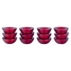 Scandinavian glass artist. Set of twelve candle holders in burgundy-red glass.