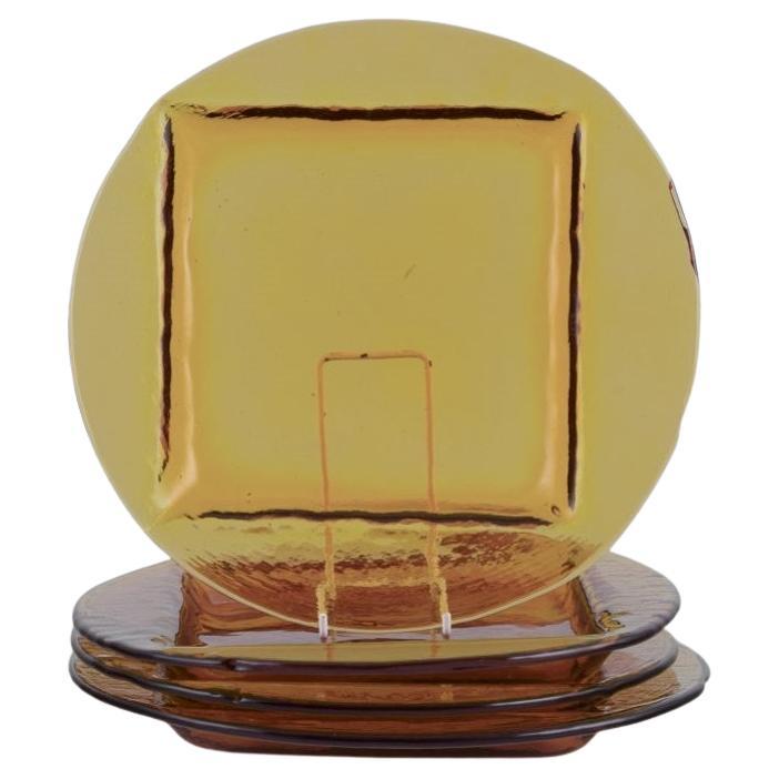 Scandinavian glass designer. Set of four dinner plates in smoke-coloured glass