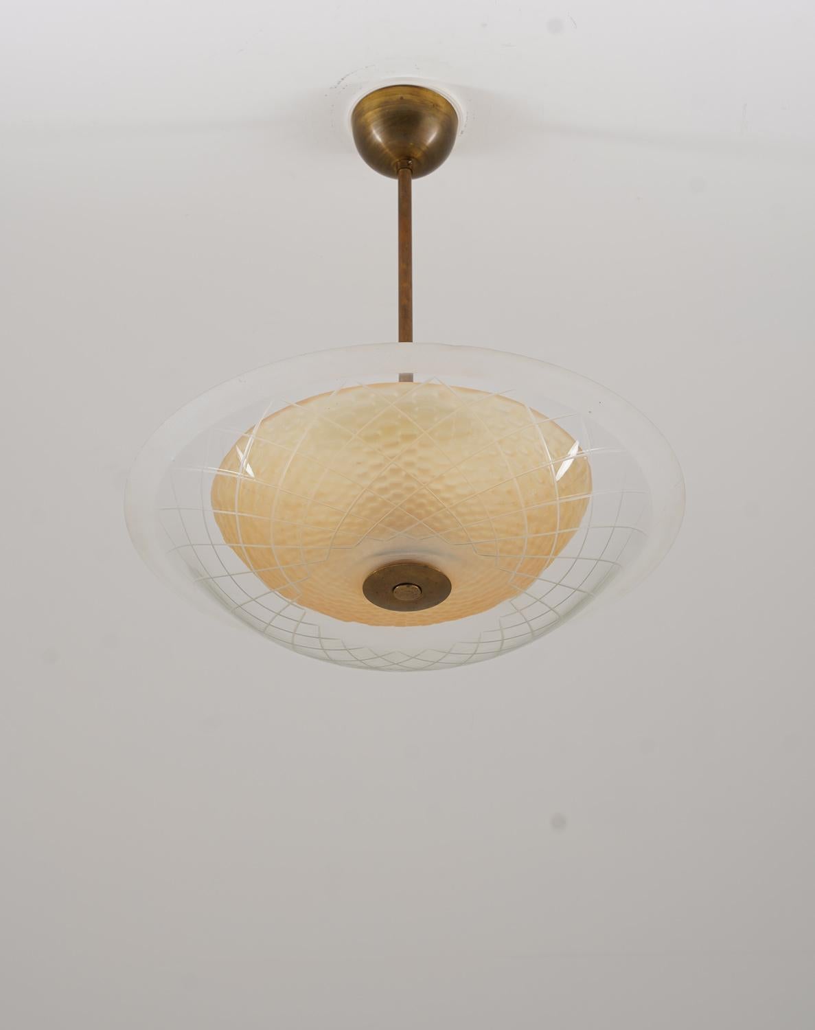 Beautiful flush mount in brass and glass, produced in Sweden circa 1950.
The lamp consists of an amber-colored inner shade, hiding three light bulbs. The inner shade is surrounded by a large outer shade in clear glass. 

Condition: Very good