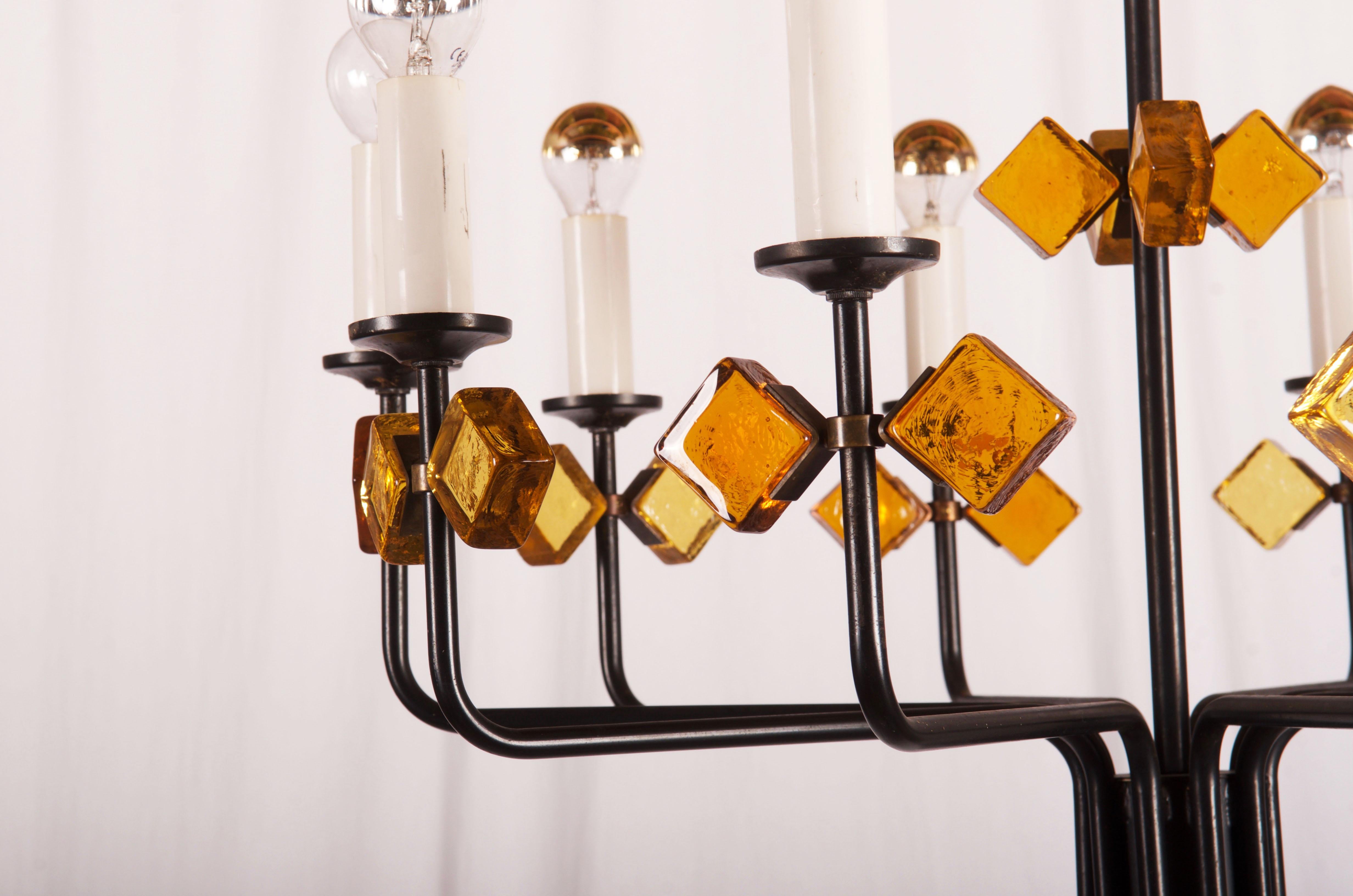 Struttura in ferro verniciato nero con elementi in vetro giallo e arancione fissati con anello e supporti in ottone. Dotato di dieci prese E14. Progettata in Danimarca negli anni '50 da Svend Aage Holm Sorensen per Holm Sorensen and Company.
 