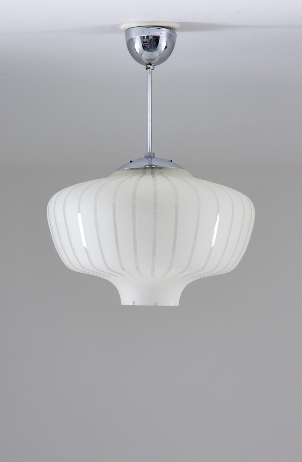 An exquisite and elegantly formed pendant light, crafted in a harmonious blend of gleaming chrome and frosted glass, adds a touch of sophistication and refinement to any space. Produced in Sweden during the 1940s, this pendant light is a true work