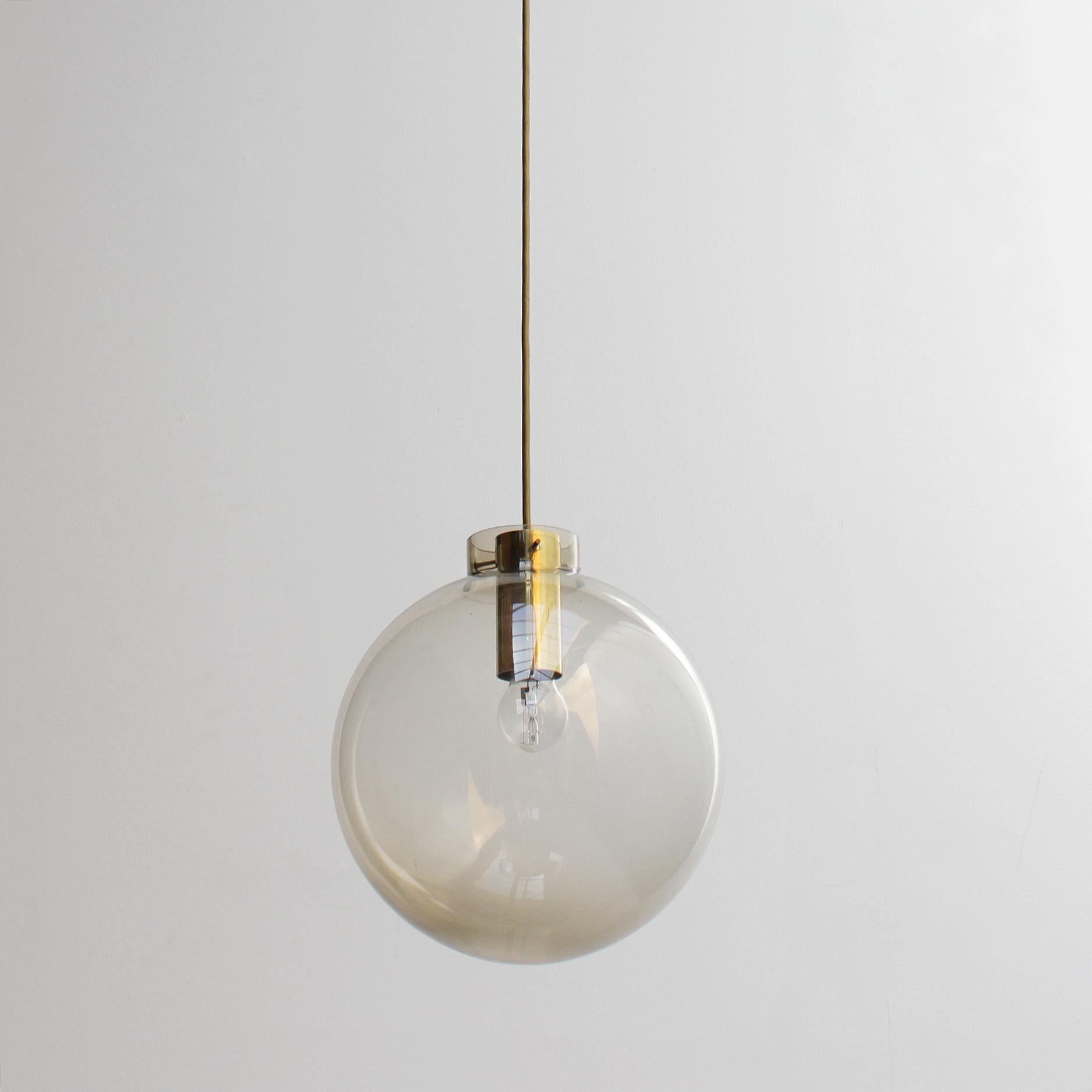 Pendant with a large smoke glass sphere, brass details and ceiling plate. Beautifully crafted details and construction, well and solidly executed. 
Diameter of the sphere: 11.5 inches (29 cm), length wire about 23.0 in. (60 cm). 
Bulb (E27 26-27