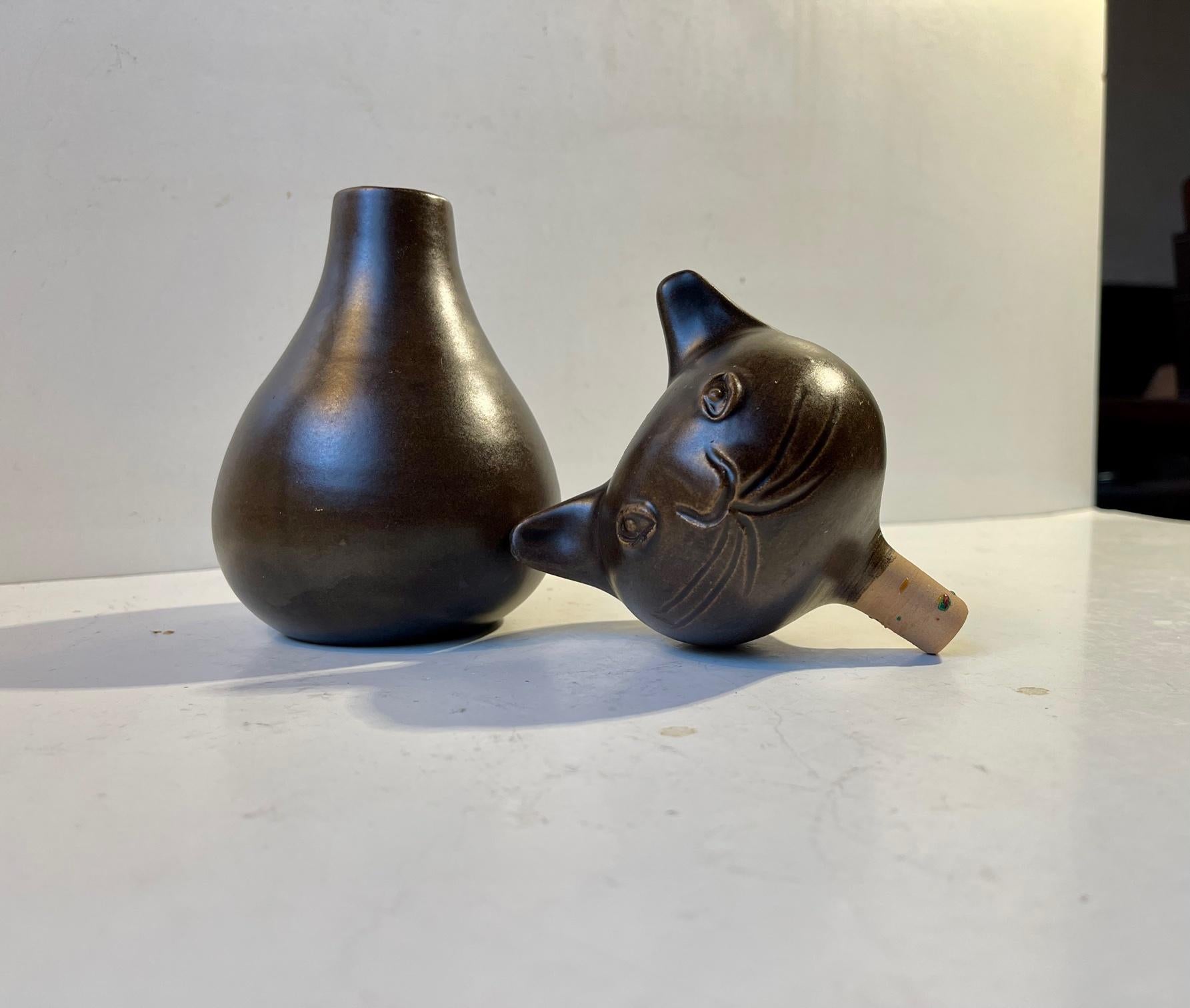 Unusual piece unique from the danish ceramist Bjerre. A dark brown glazed ceramic cat that is intended as a vase/decorative object but also can be used as a decanter. It is signed Bjerre and the year 75. Measurements: H: 21 cm, W: 9 cm (at the head).