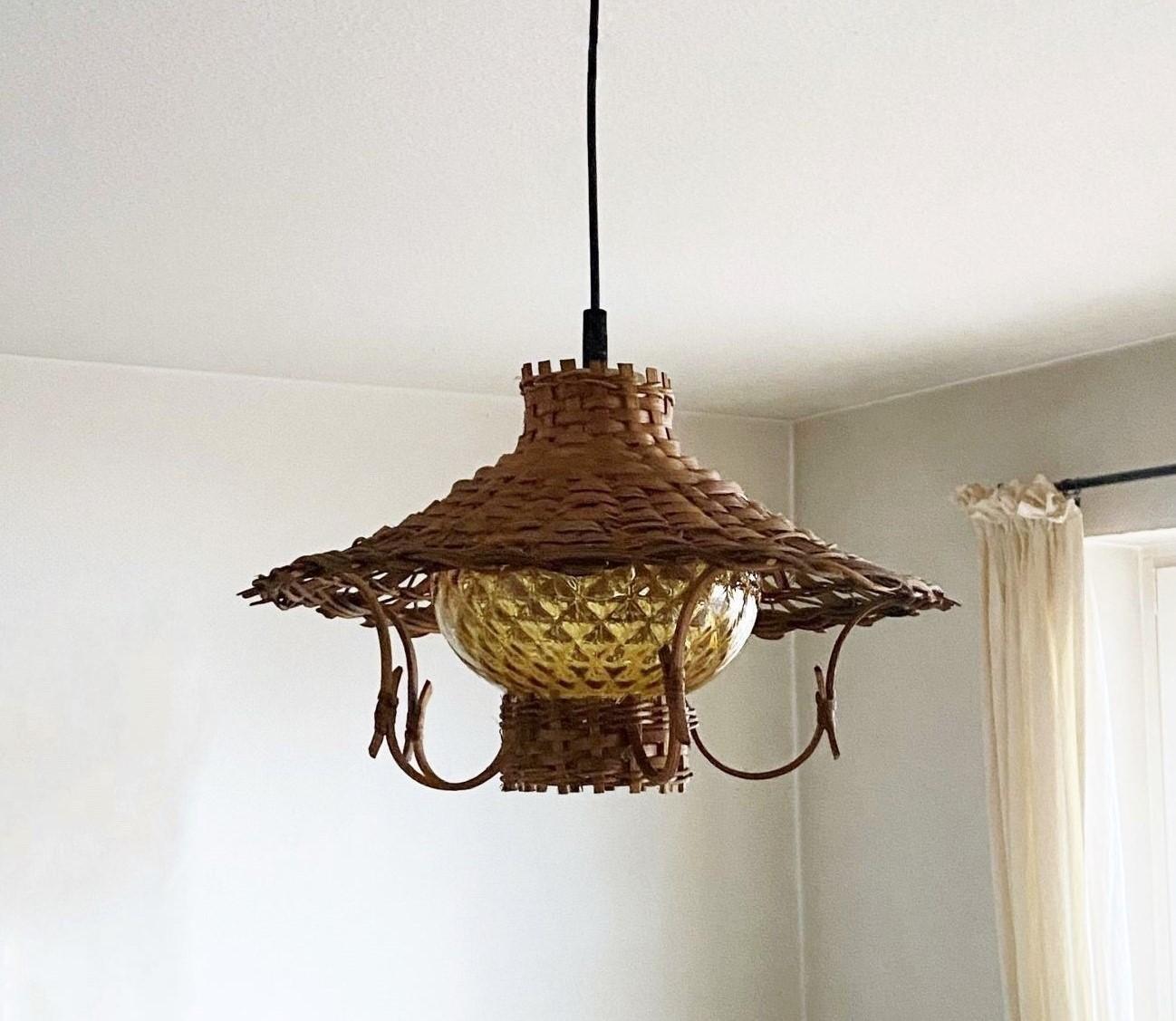 A lovely true Vintage Scandinavian hand-woven rattan pendant, Denmark, 1960s, with a hurricane amber glass shade provinding a warm and pleasant light. This beautiful lamp is in fine vintage condition, no damages, rewired. It takes one Edison E27