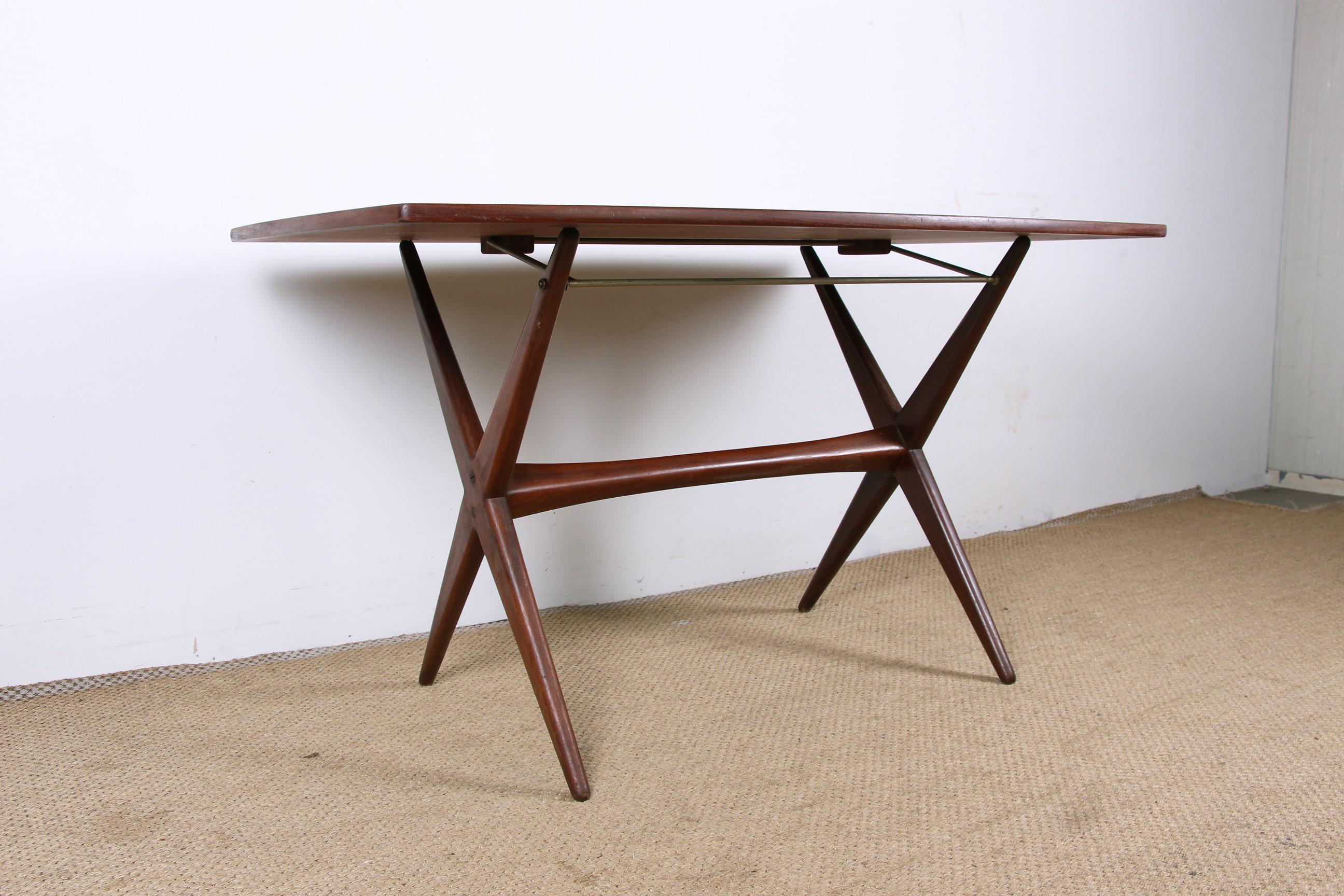 Rare and clever table that can be used as a dining table or as a large coffee table. 
A clever brass mechanism makes it easy to change the height of the table. 
With its double X-shaped base connected by a spacer and its slightly oblong top, it