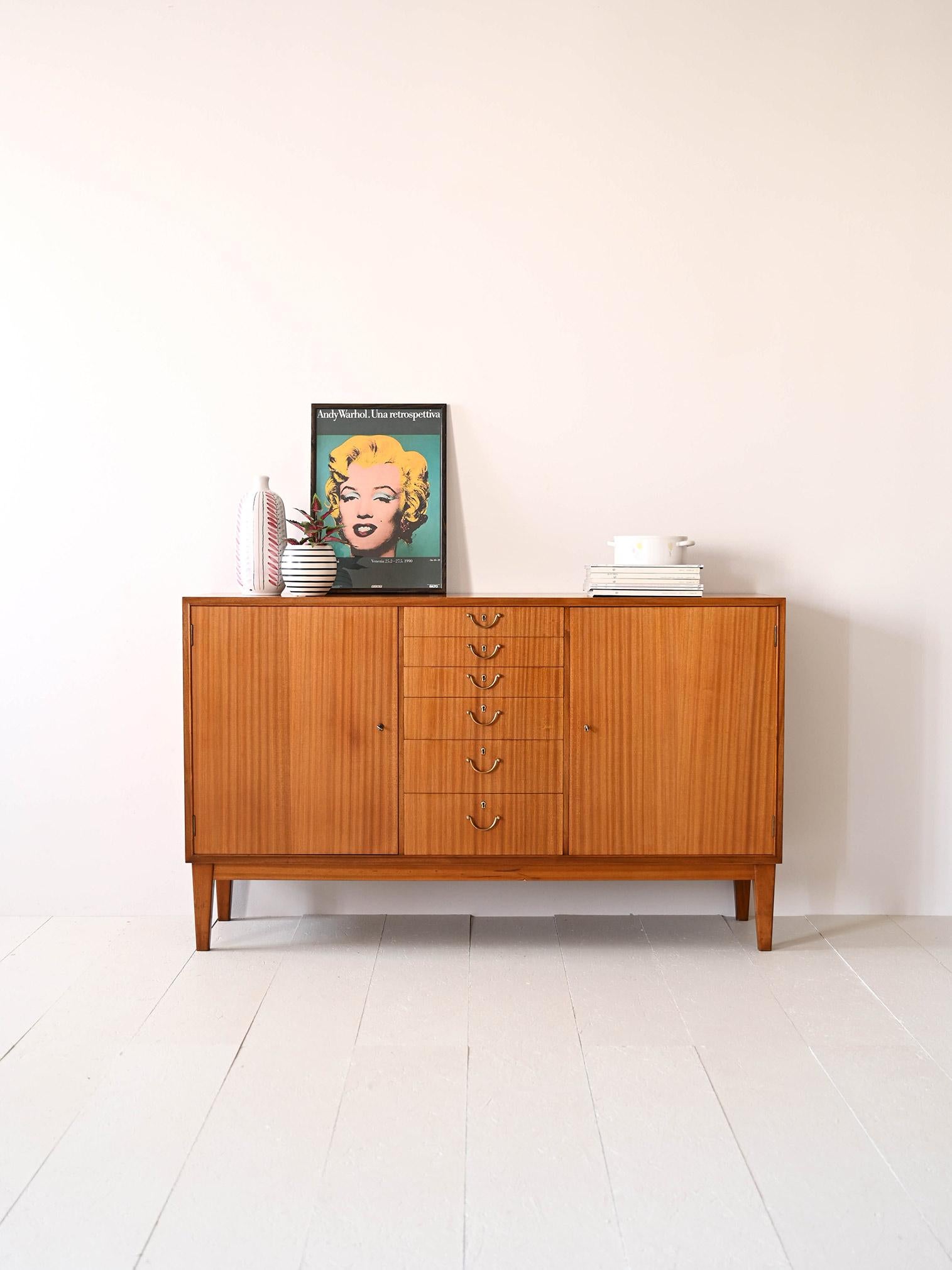 1950s sideboard cabinet of Scandinavian provenance with central drawers.

A piece of furniture that traces the lines of mid-century design.  The six drawers with metal handles are located in the center of the cabinet, while on either side are two