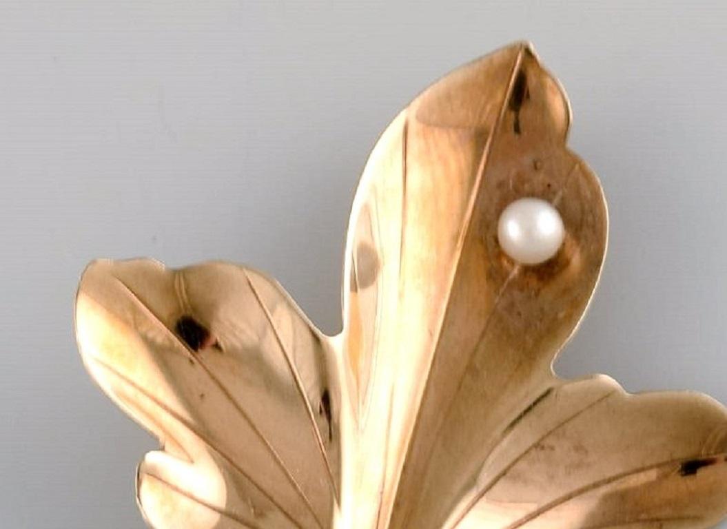 Skandinavischer Juwelier. Blattförmige Brosche aus 14-karätigem Gold, verziert mit einer Zuchtperle. Mitte des 20. Jahrhunderts.
Maße: 4 x 4 cm.
In ausgezeichnetem Zustand.
Gestempelt.
Misst bis zu 14 Karat beim Juwelier.