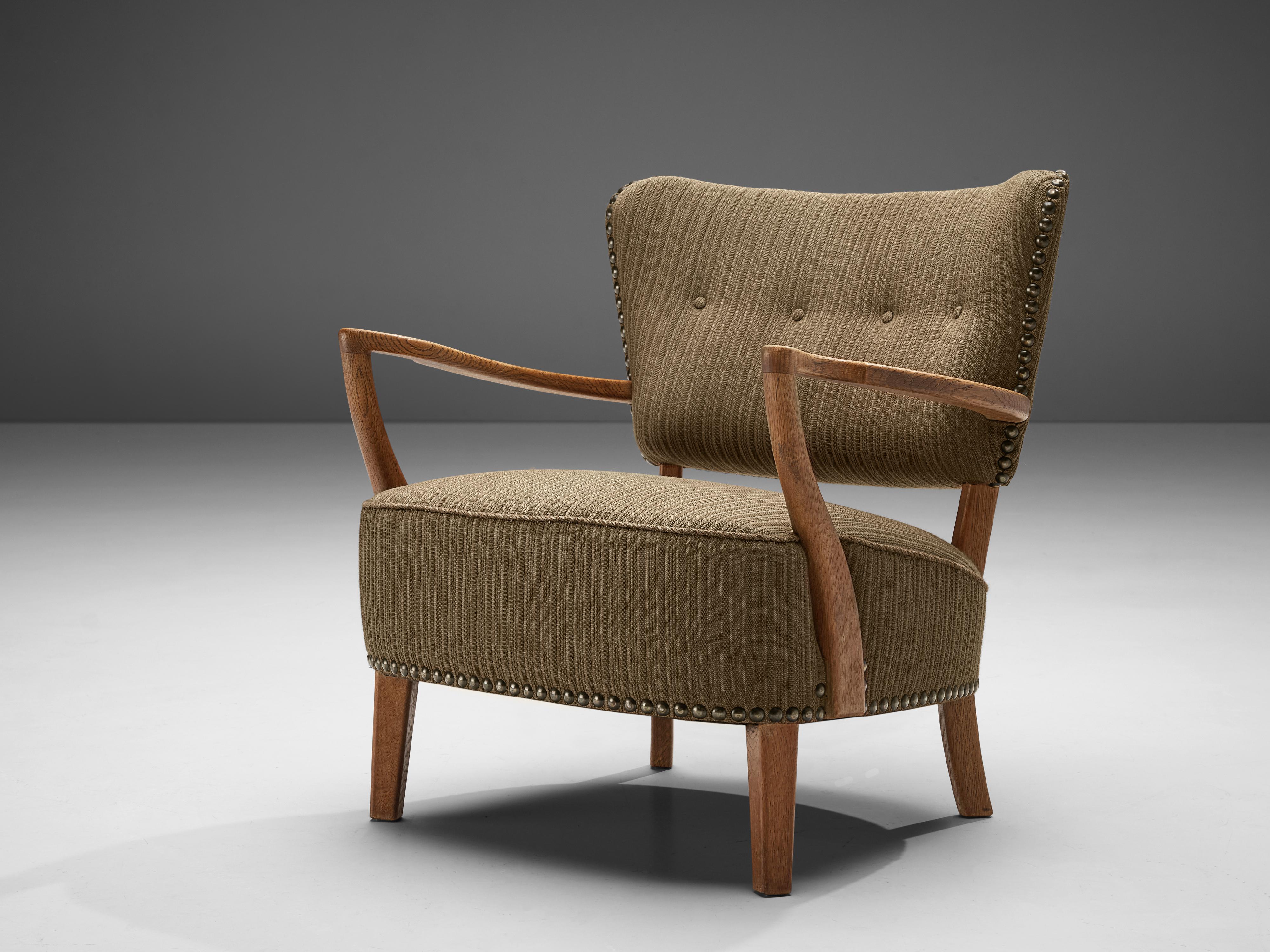Lounge chair, fabric, metal, oak, Scandinavia, 1950s.

The present armchair is a great example of Scandinavian Modern design. The green brown fabric features subtle stripes and is affixed to the frame with notable metal nails. Tufted details on