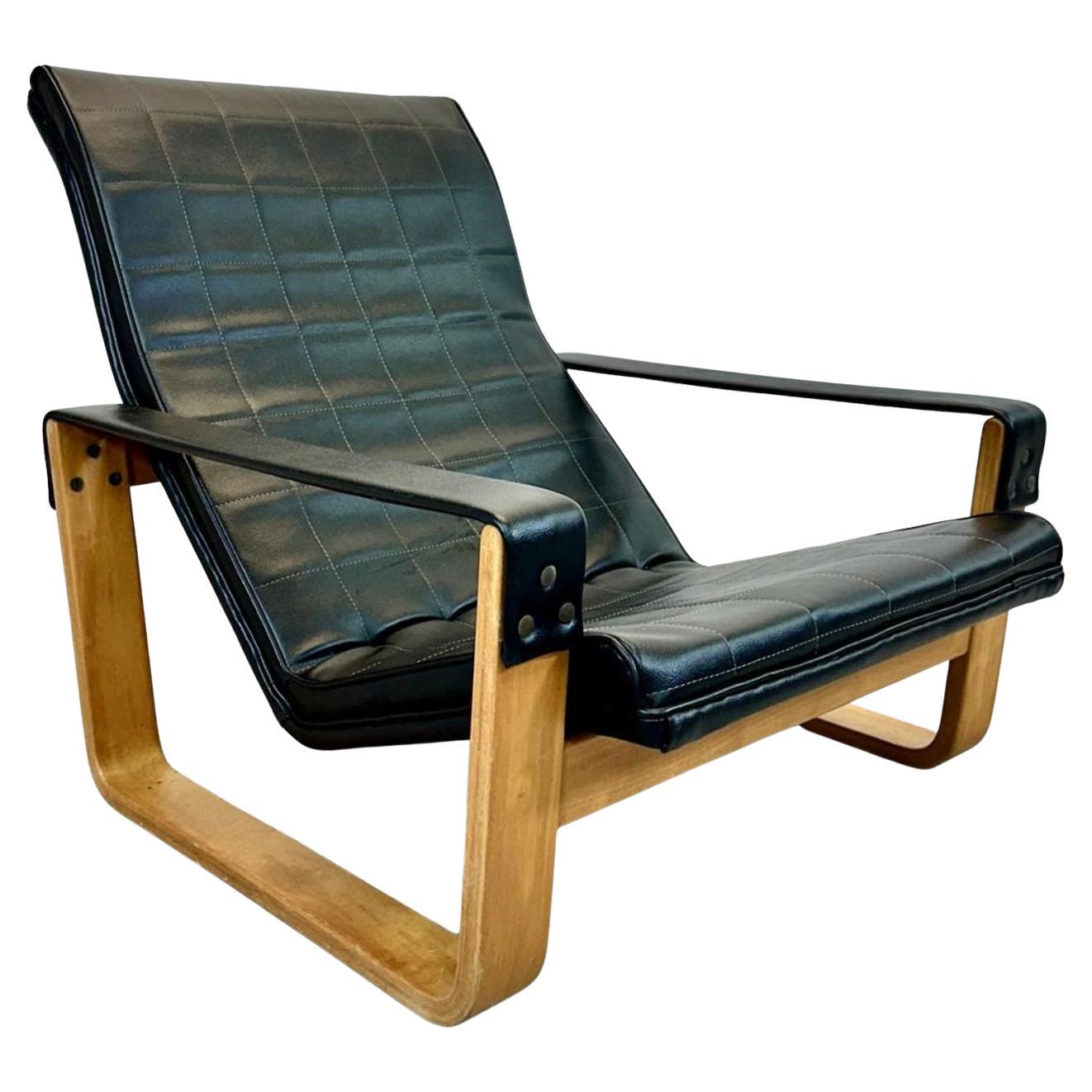 Mid century Asko Pulkka faux leather sling arm lounge chair in black with birch bentwood, in very good condition. The upholstery has square quilting pattern and is in very good condition and only shows a little wear. Made in Finland. Located in