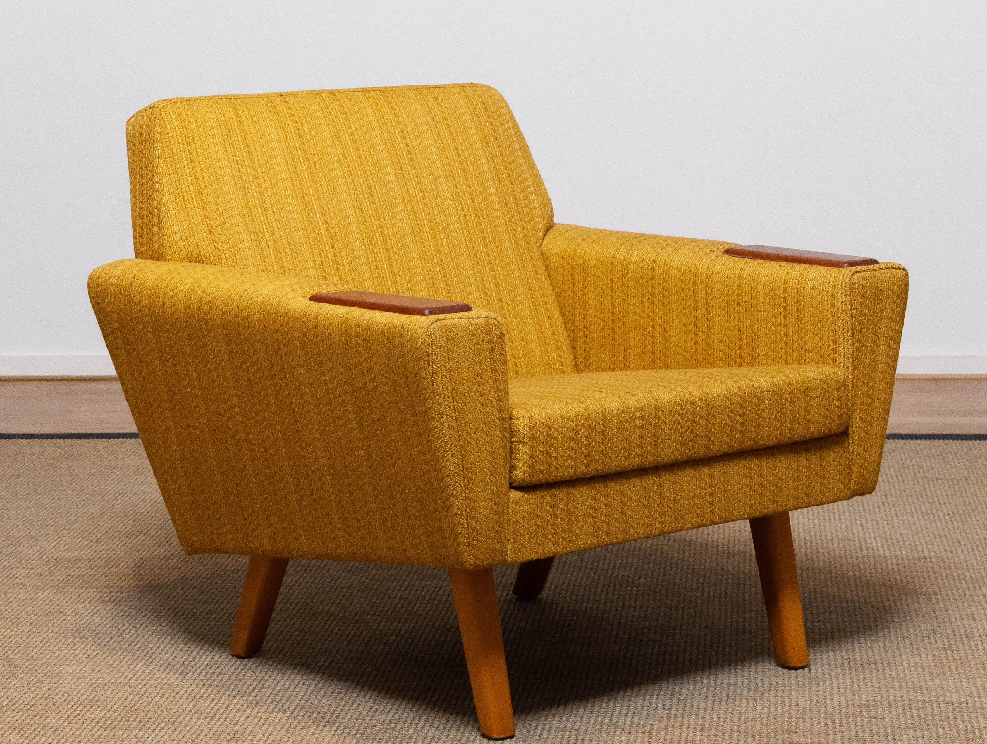 Absolutely beautiful and typical Scandinavian mid century lounge chair in yellow / ochre and a little brown blended colored woolen fabric in complete original condition. This chair supports and sits very good and is in allover very good condition as