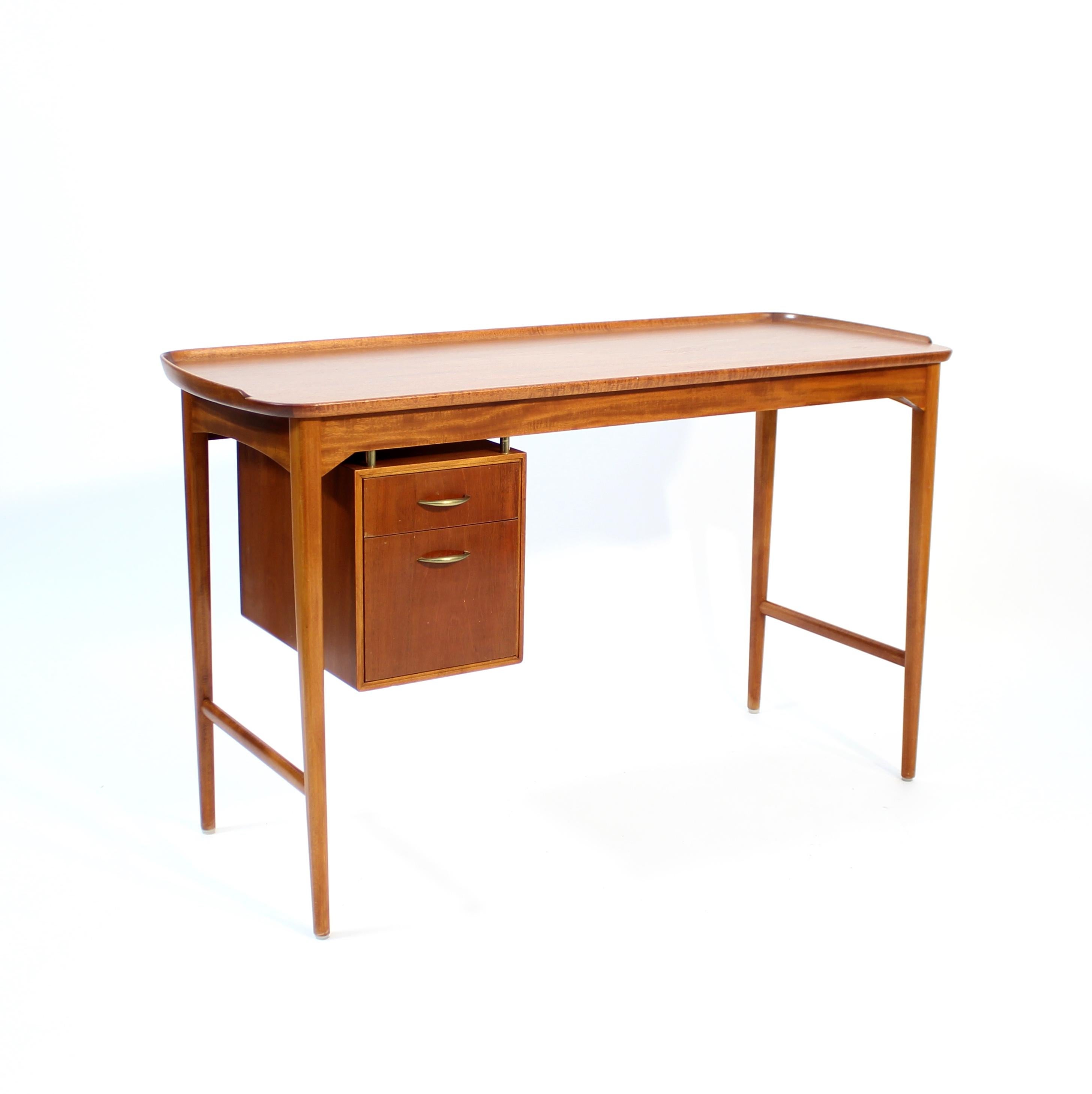 Smaller freestanding Swedish Mahogany desk with two drawers and a rim around the desk top. The two drawers has brass handles and the lower drawer have four storage departments in it. The desk is very light in appearance due to the thin and elegant