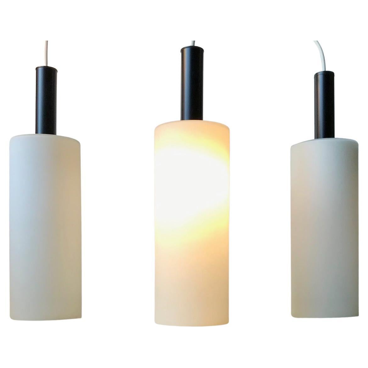 A trio of 'hammer' or 'mallet' shaped pendant lamps composed of matté cased opaline glass and top made from powder coated steel. Designed and manufactured by Lyfa in Denmark during the 1970s in a style reminiscent of Stilnovo. Measurements: H: 39