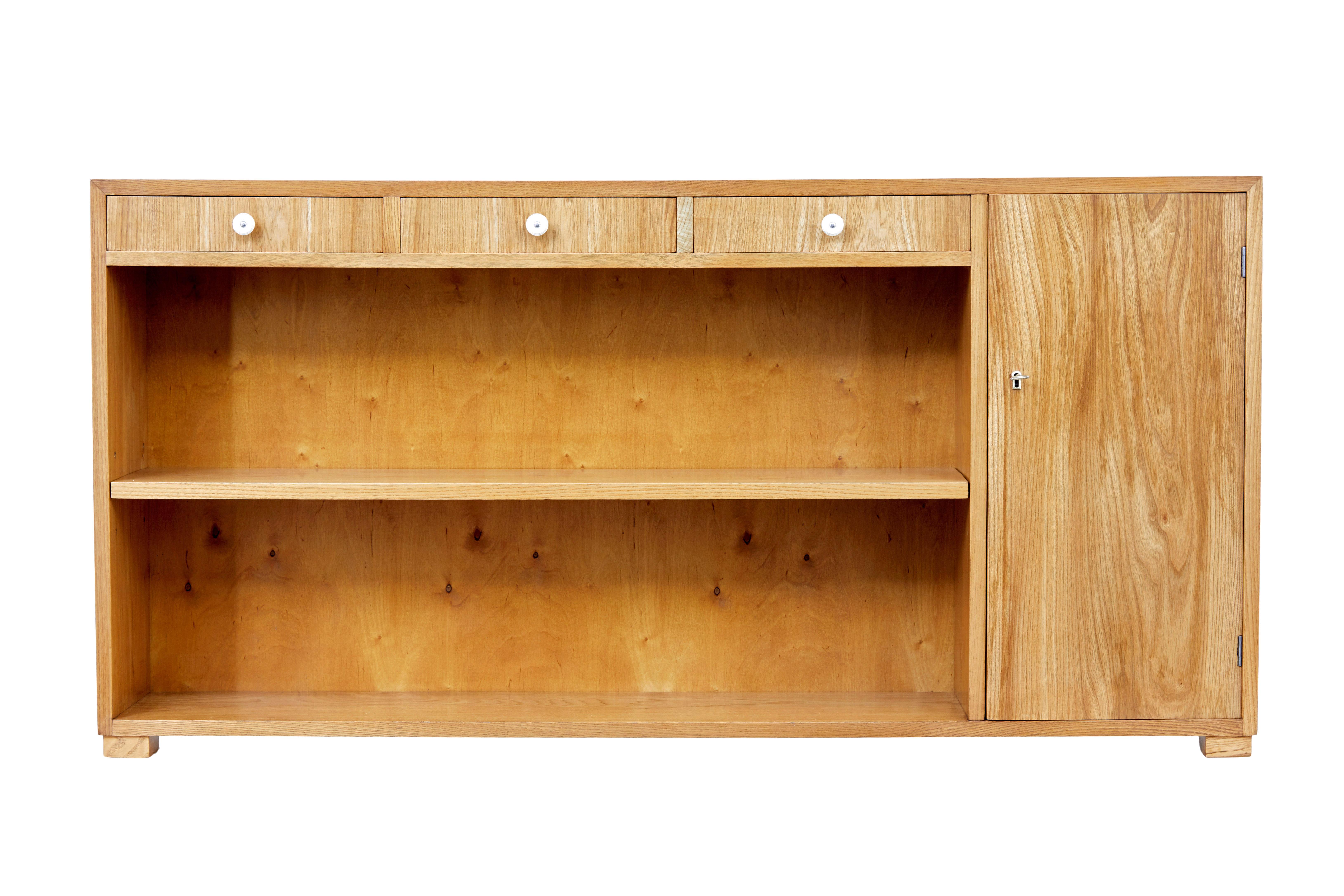 Scandinavian mid 20th century low elm bookcase circa 1950.

Good quality low open bookcase which is ideal for those smaller spaces.

Veneered in elm, rectangular shaped and only 10 inches deep.  3 drawers below the top surface each fitted with a