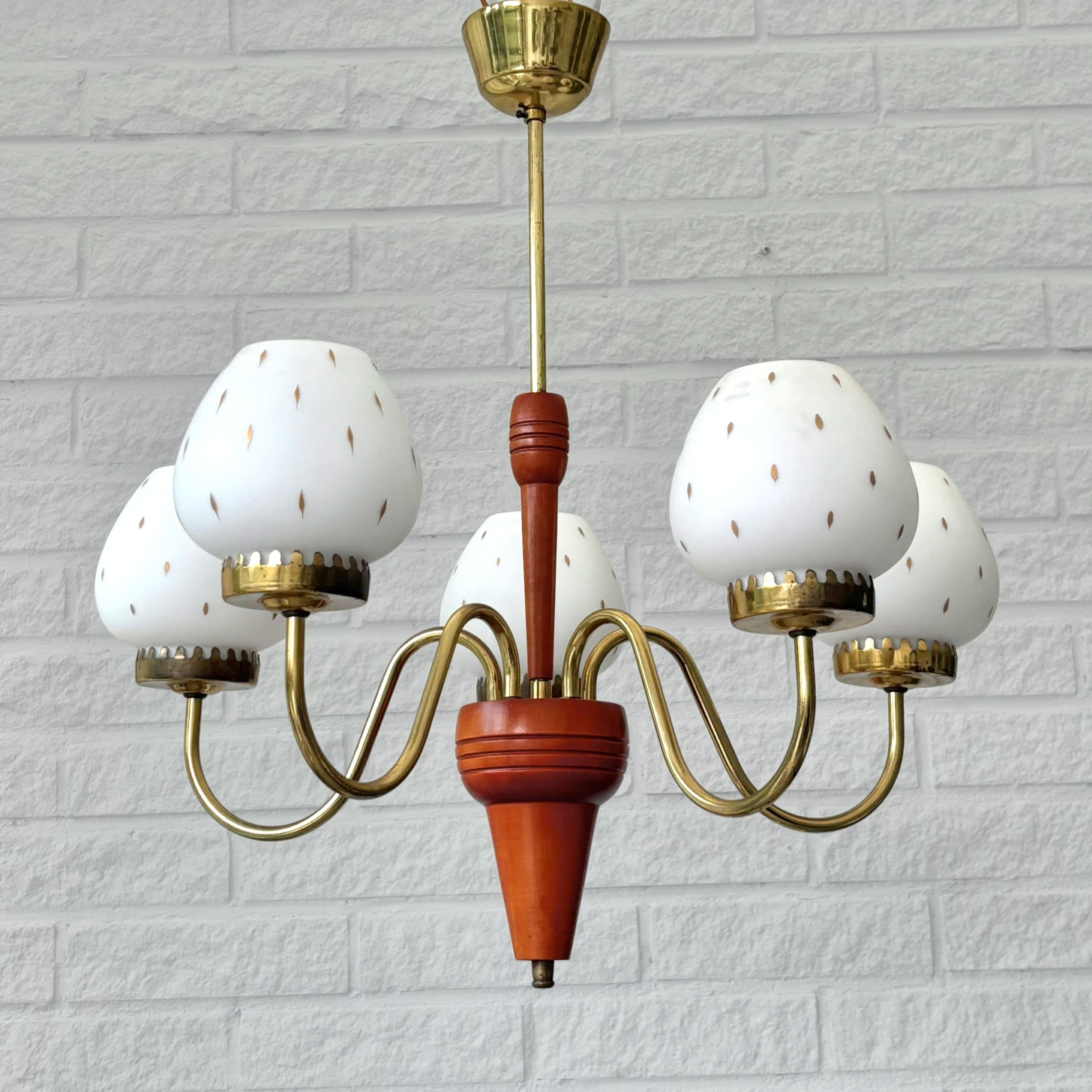 Lampadario scandinavo della metà del secolo scorso, prodotto da un produttore svedese non identificato negli anni '50. Realizzato in ottone, presenta cinque bracci curvi che si estendono da un centro scultoreo realizzato in betulla colorata. Ogni