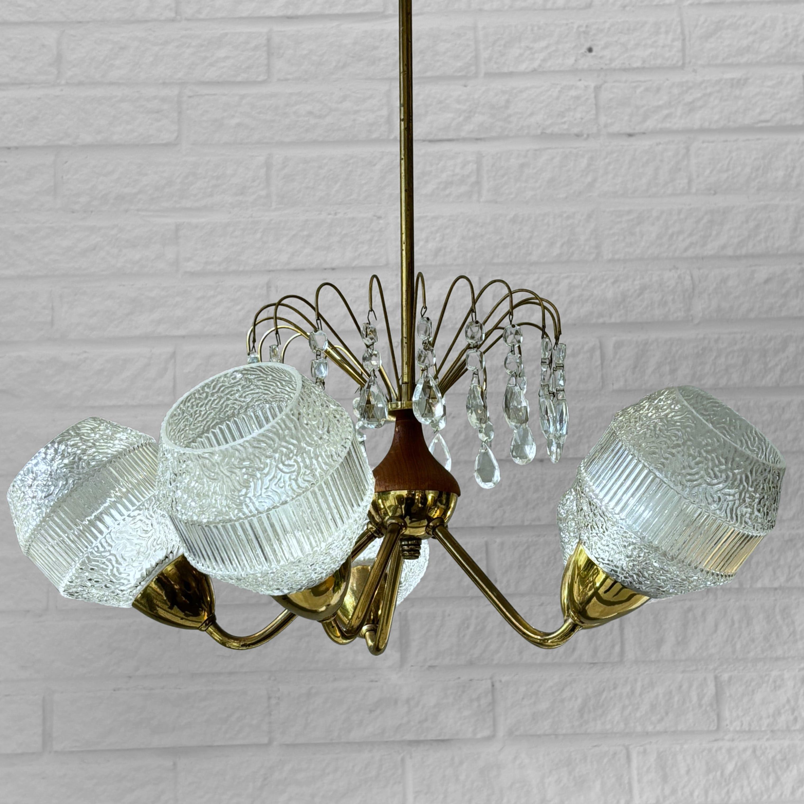 Lampadario scandinavo della metà del secolo scorso, prodotto da un produttore svedese non identificato negli anni '50. Realizzata in ottone, presenta cinque bracci curvi che si estendono da un elemento centrale in teak, ciascuno dei quali sostiene
