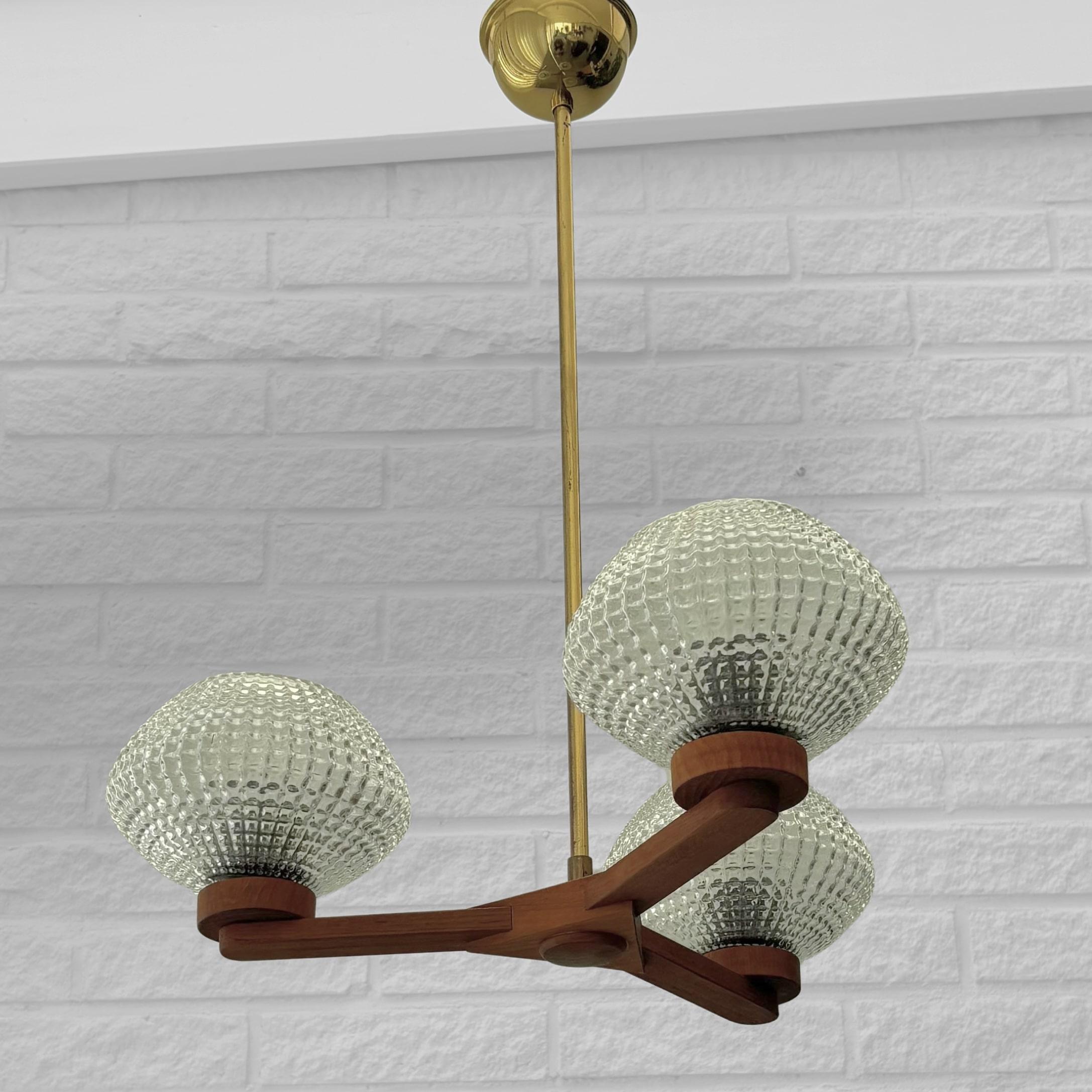 Lampadario scandinavo di metà secolo, prodotto da un produttore svedese non identificato negli anni '50. Il design combina il caldo teak naturale con i dettagli in ottone lucido, esemplificando l'equilibrio tra materiali organici e forme moderniste