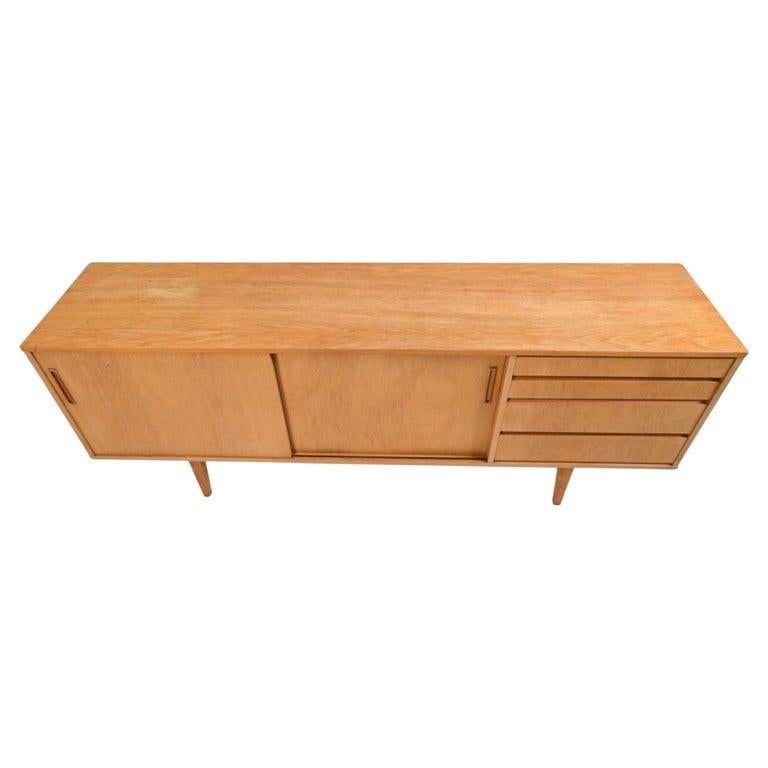 Scandinavian Mid Century Danish Modern light oak 4 drawer 2 door credenza. Beautiful sideboard in light oak that has (4) drawer and (2) sliding doors with 2 adjustable shelves. Interior finished in teak. In the manner of Arne Vodder. Scandinavian