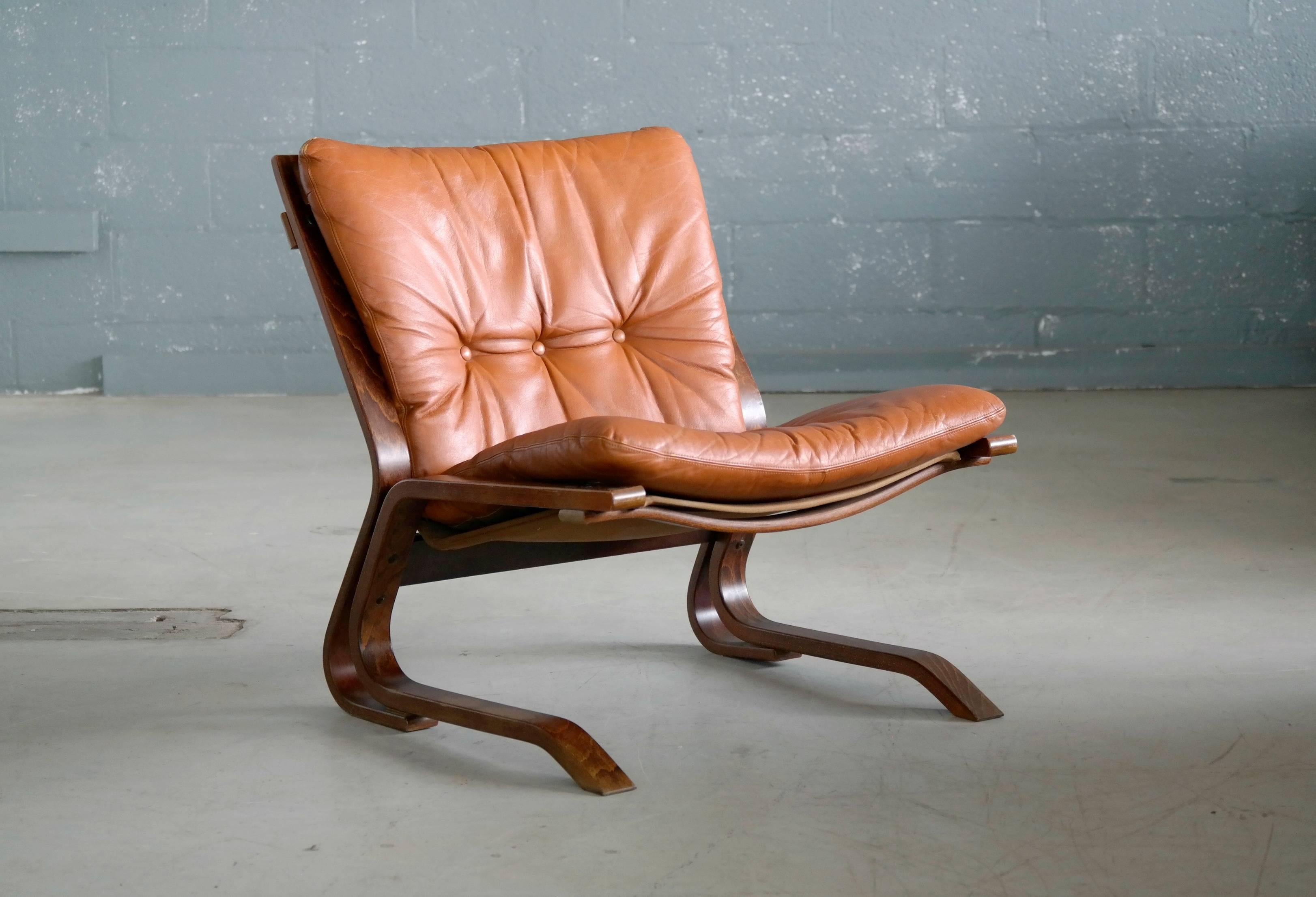 Beautiful easy chair in rosewood stained laminated beechwood with cognac colored cushion in a canvas sling designed circa 1967 by Oddvin Rykken of Norway and produced early 1970s by Rykken and Co. While similar in style to the popular designs by