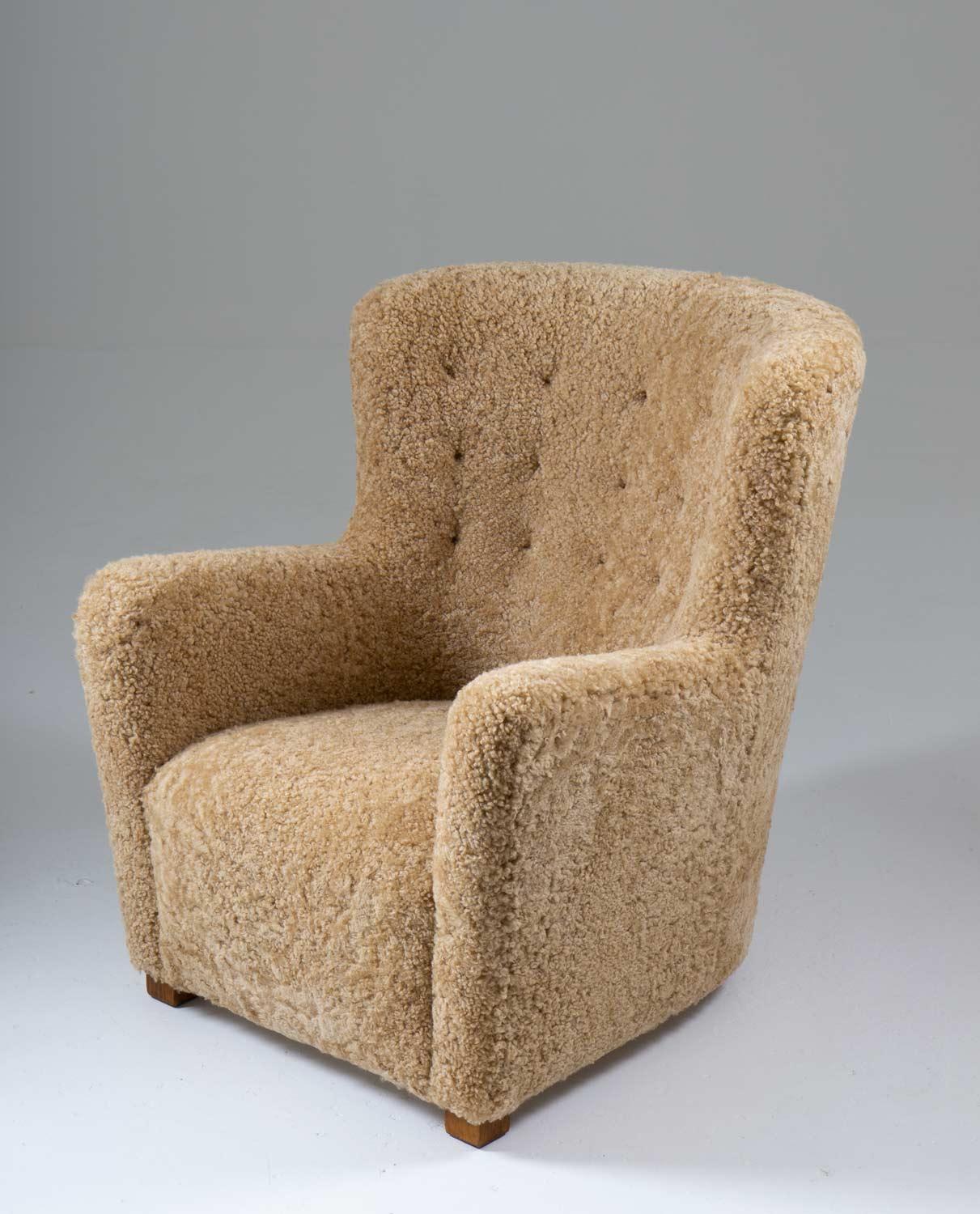 High-back lounge chair manufactured in Denmark ca 1940. 
This majestic chair surrounds you with its curved backrest and it is just as comfortable as it looks. 
It's been reupholstered in honey colored sheepskin and cognac leather