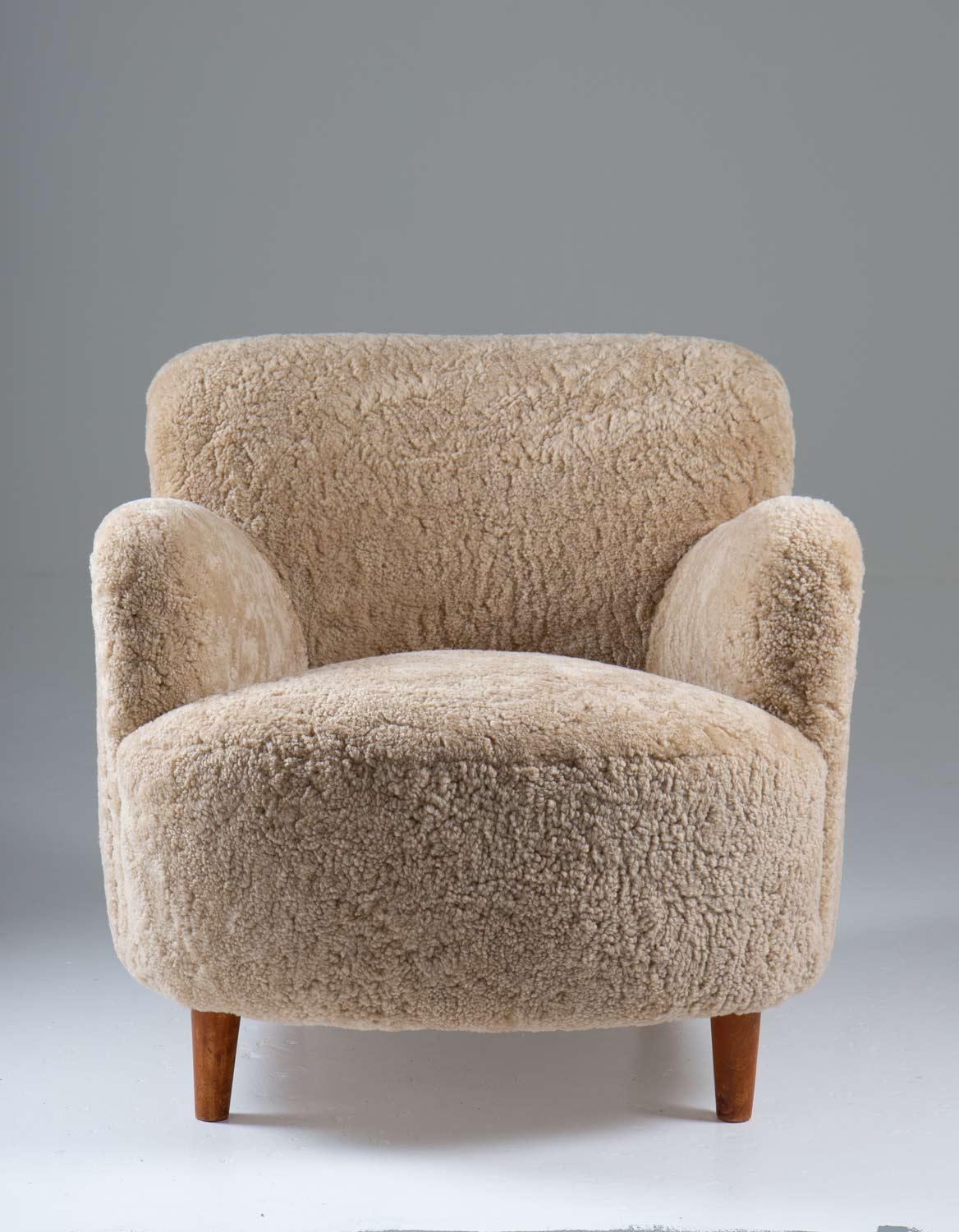 Low-back lounge chairs manufactured in Sweden ca 1940. 
Cozy lounge chairs with exceptional proportions and design. 
They have been reupholstered in ivory-colored sheepskin.

Condition: Excellent, fully restored and reupholstered, signs of age