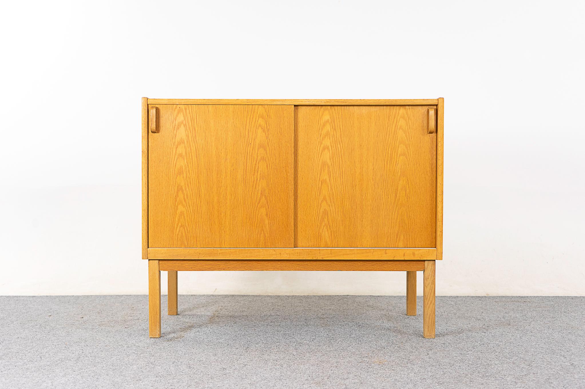 Oak Scandinavian cabinet, circa 1960's. Clean, simple lined design with book-matched veneer. Sliding doors open to a fixed shelf. Lovely practicle size! 

Unrestored item with option to purchase in restored condition for an additional $150 USD.