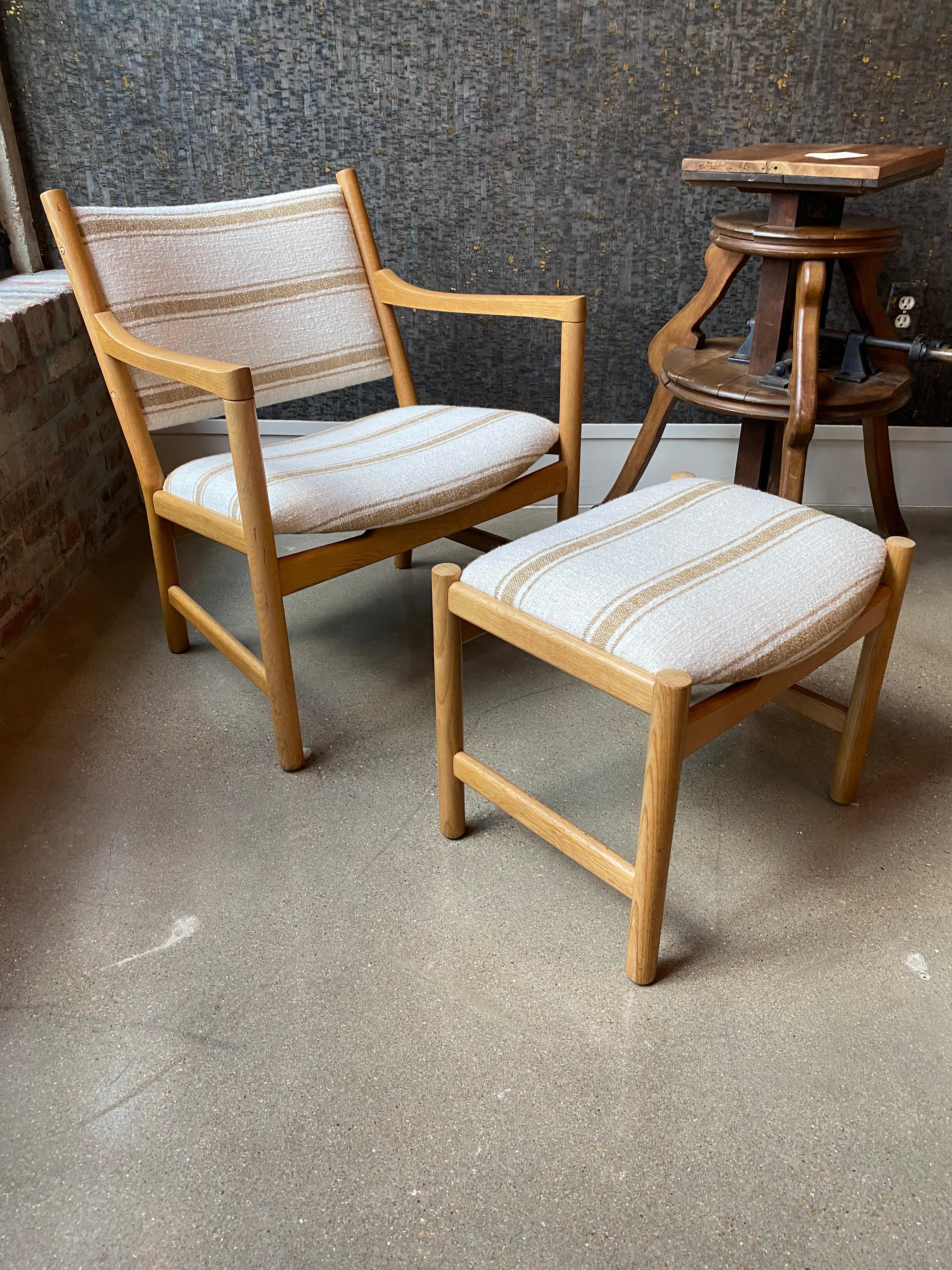 Mid-century Scandinavian/Danish chair with oak frame and upholstered seat and back. The chair comes with a matching ottoman or footstool.  Newly upholstered in camel and white striped heavily woven linen by Bruder. This is a very comfortable set,