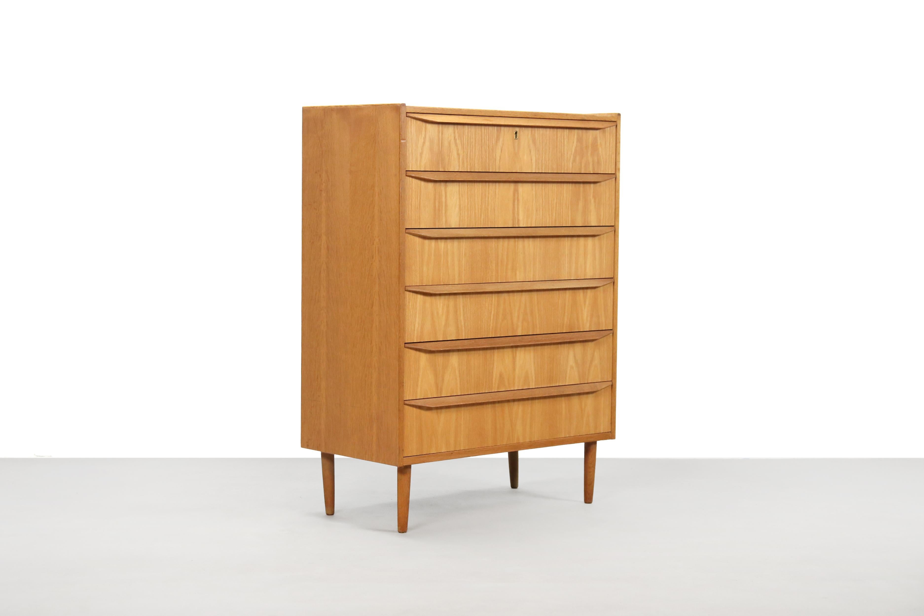 Danish modern design chest of drawers with 6 drawers. Made of oak wood with beautiful continuous handles across the width of the drawers. This chest of drawers comes from the 1970s from Denmark. Use this cabinet in the hallway, in the bedroom for