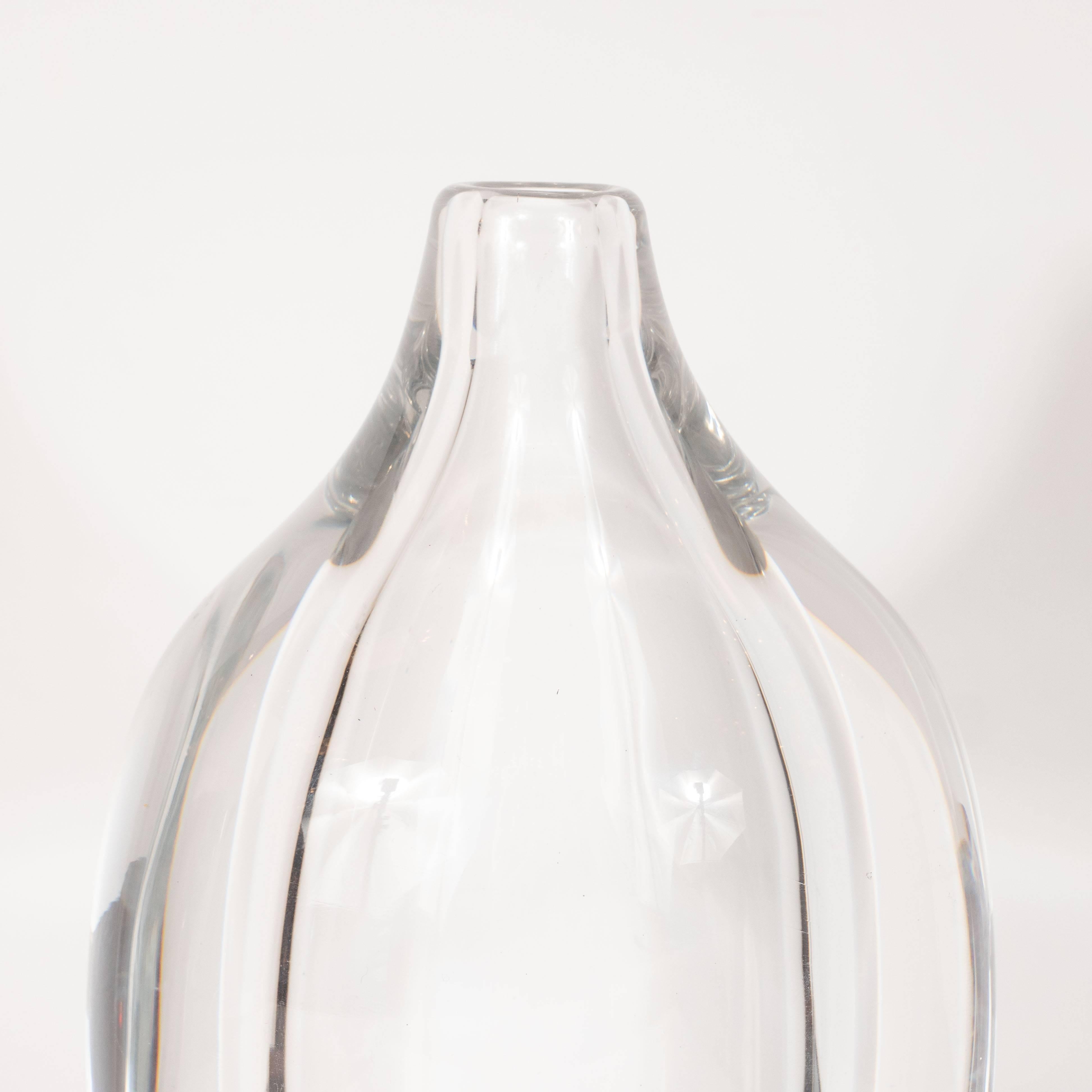 This elegant and sophisticated vase was realized by the esteemed midcentury Swedish glass studio, Orrefors, circa 1960. It features an ovoid form- with a concentric form of the same shape inlaid in the center- sloped shoulders and a narrow circular