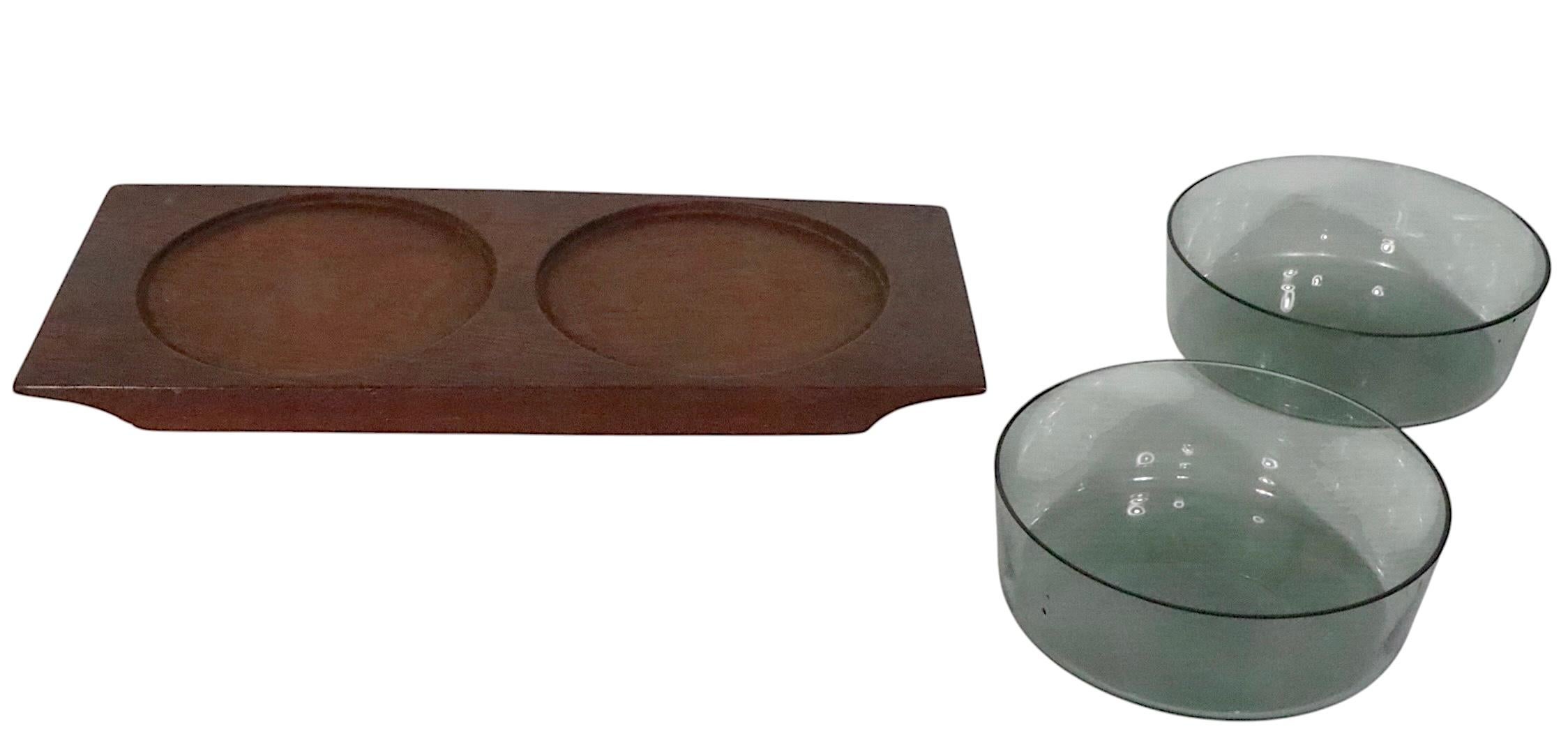 Rare Scandinavian Mid Century Modern serving dish, made in Finland by Nuutajarvi Notsjo, circa 1950's. The dish includes a solid teak  base with two original tinted glass serving bowls. Fully and correctly marked on verso. 