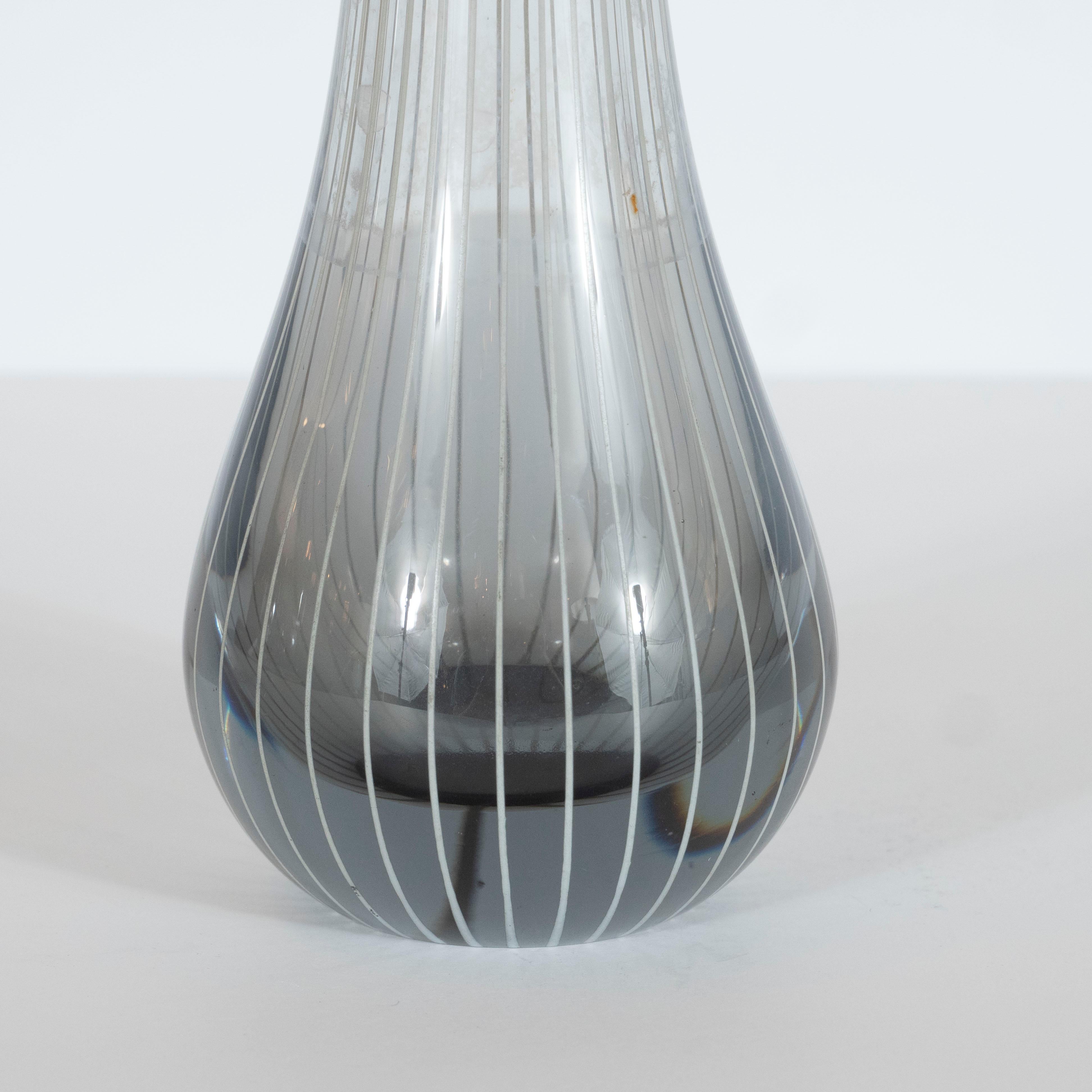 This elegant Mid-Century Modern vase was hand blown in Sweden, circa 1960. It features a undulating angular mouth and slender neck that expands into a protuberant base handblown in a sultry smoked translucent glass. The glass is striated with evenly