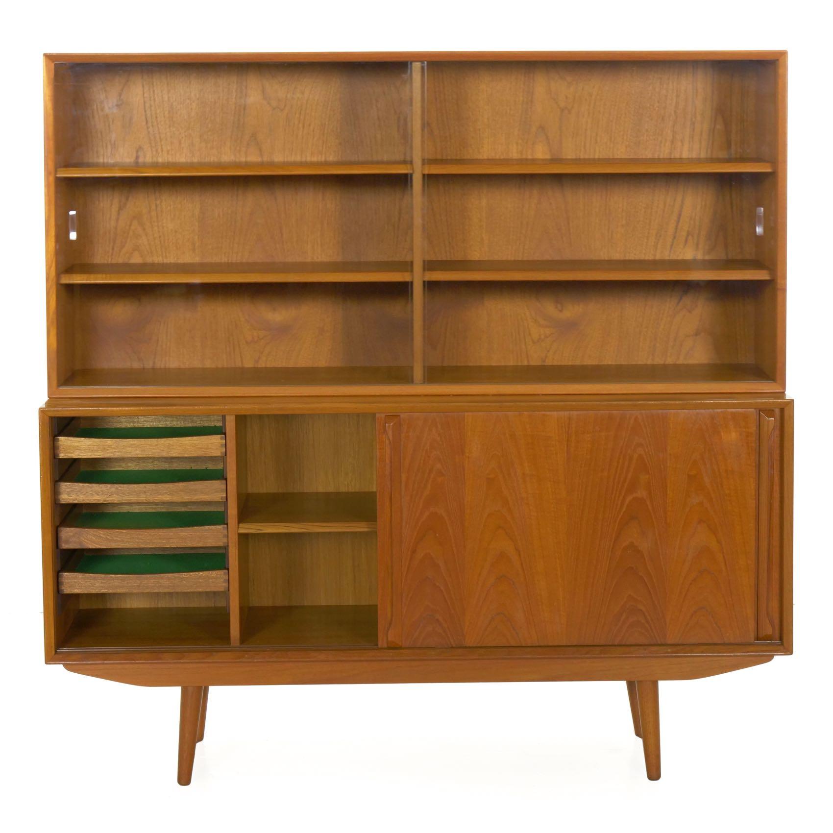 A very high quality and sleek bookcase cabinet situated over a credenza, the bookcase separates into three parts: the base, the credenza and the upper bookcase. This has likely allowed the piece to remain in its overall excellent condition over the