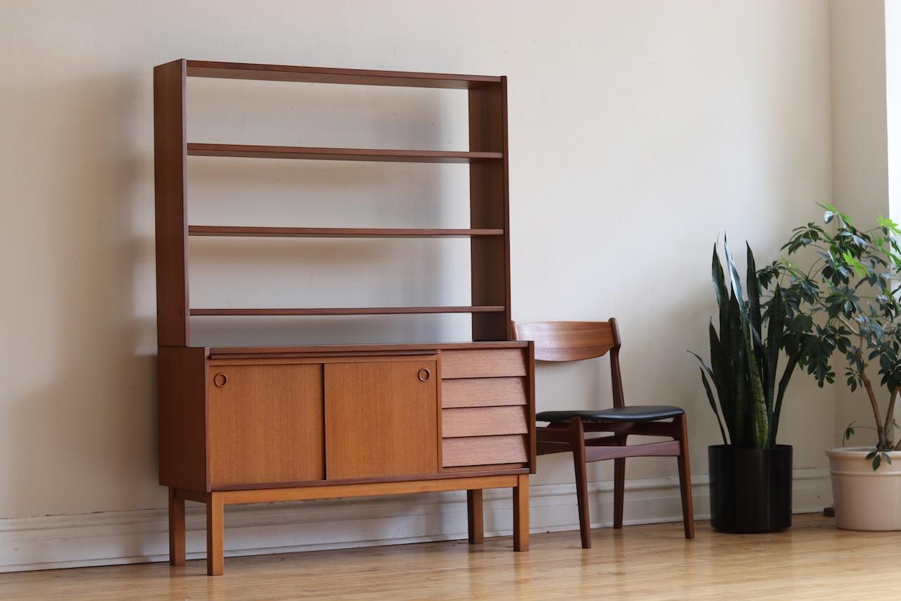 Midcentury Danish modern 2-piece teakwood shelving unit.
Just imported from Copenhagen. Made in Sweden.
Features a hidden pull-out desk that extends to create a workspace/table prep surface.
Four drawers on the bottom half. Open shelves on